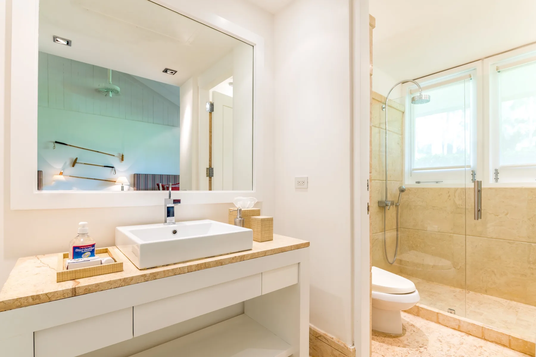A bright bathroom with a sink vanity and glass-enclosed shower.