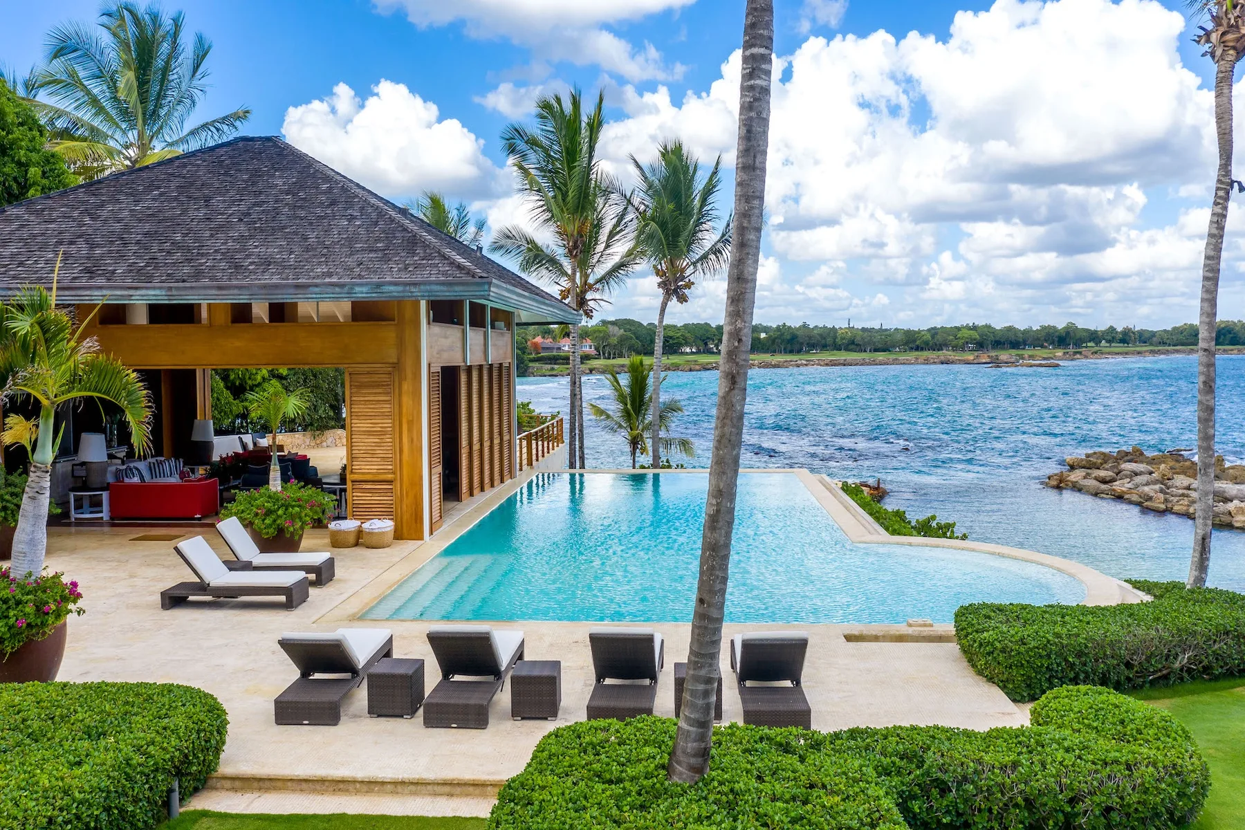 An outdoor pool beside a modern pavilion overlooks the water.