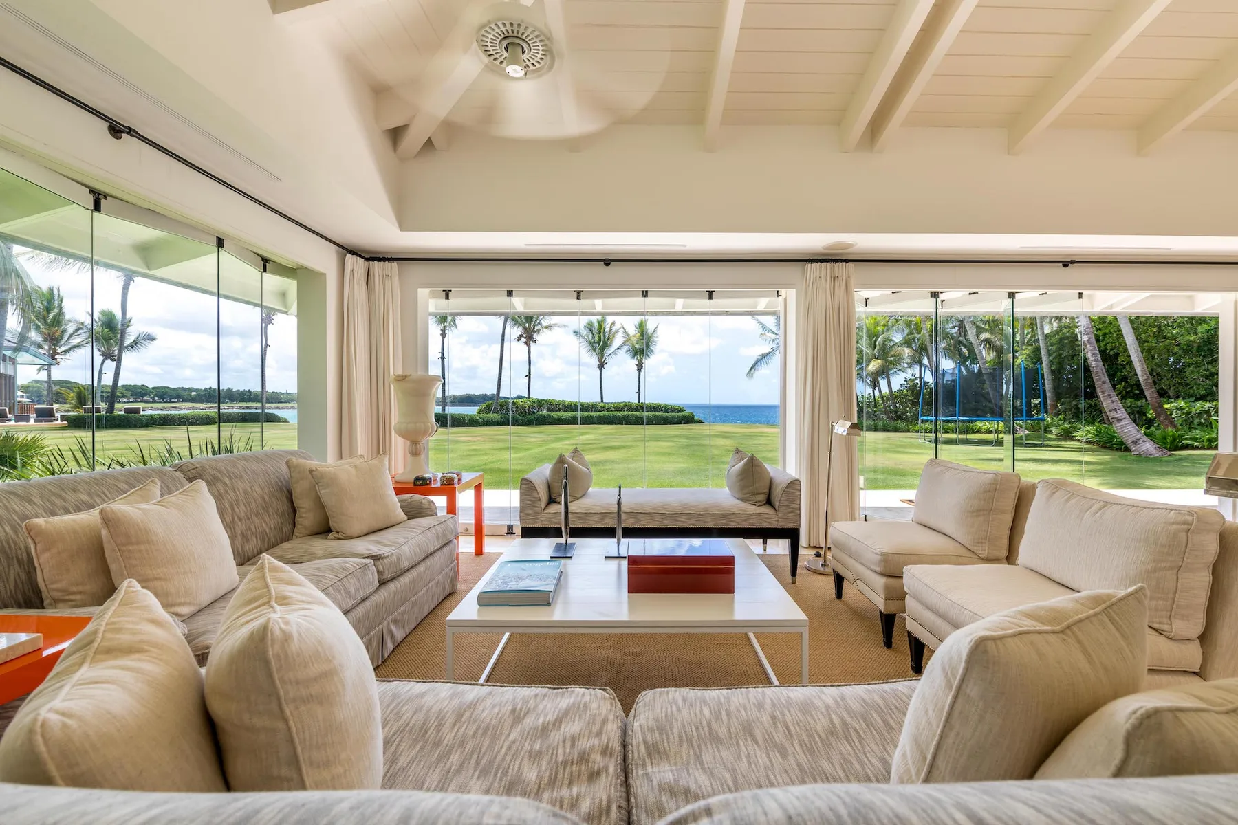 A bright living room with seating arranged around a coffee table and wide garden views.