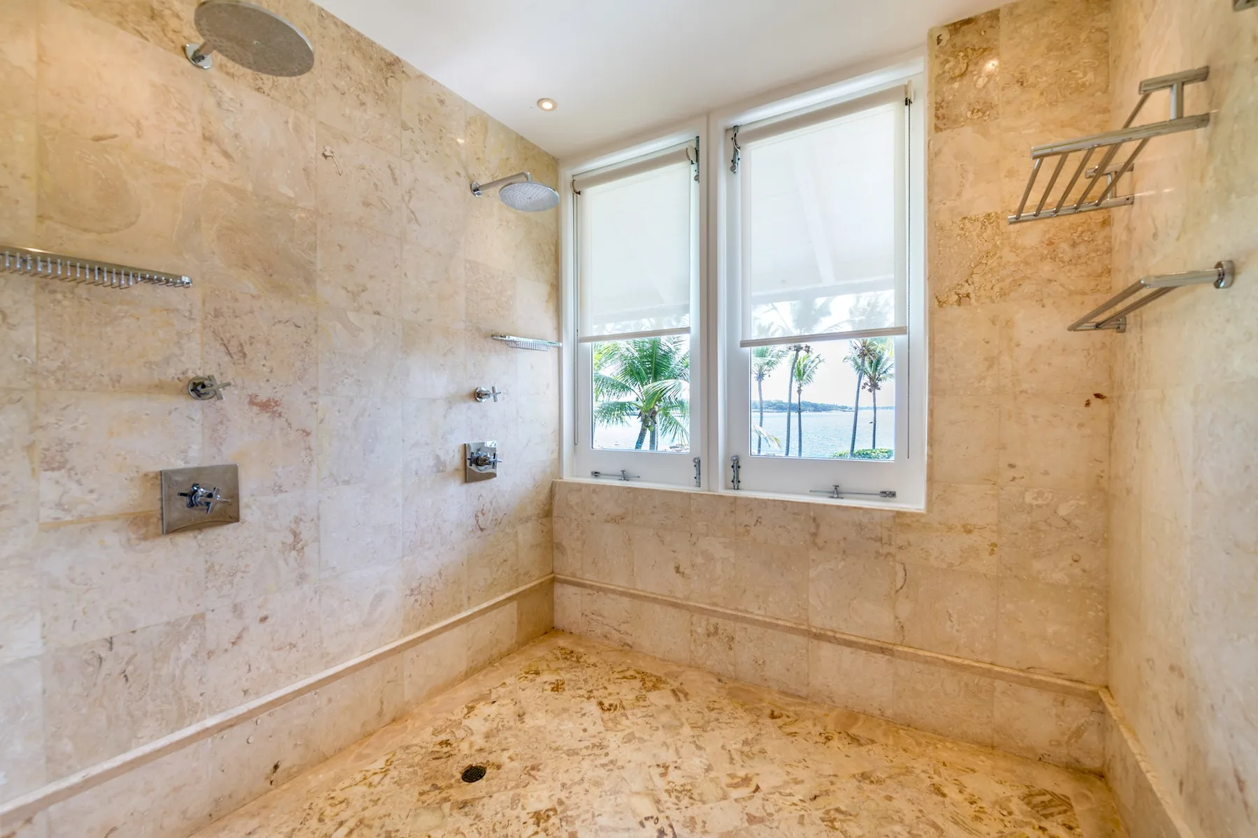 A marble-tiled shower area with two bright windows.
