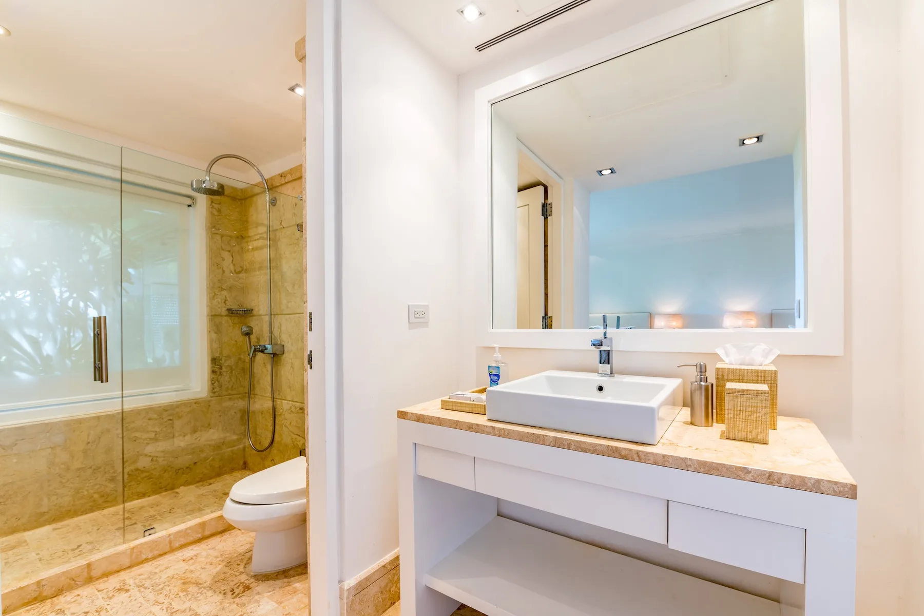 A bathroom with a sink and mirror beside a glass shower.