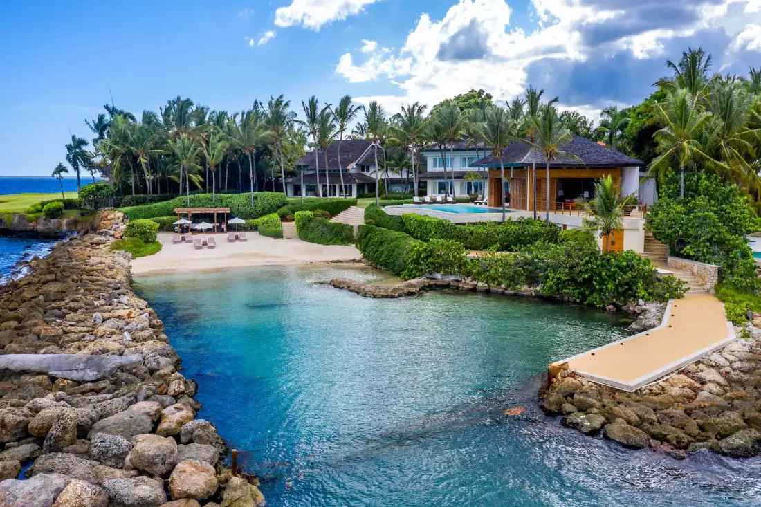 A tropical beachfront resort overlooks a sheltered turquoise inlet and landscaped grounds.