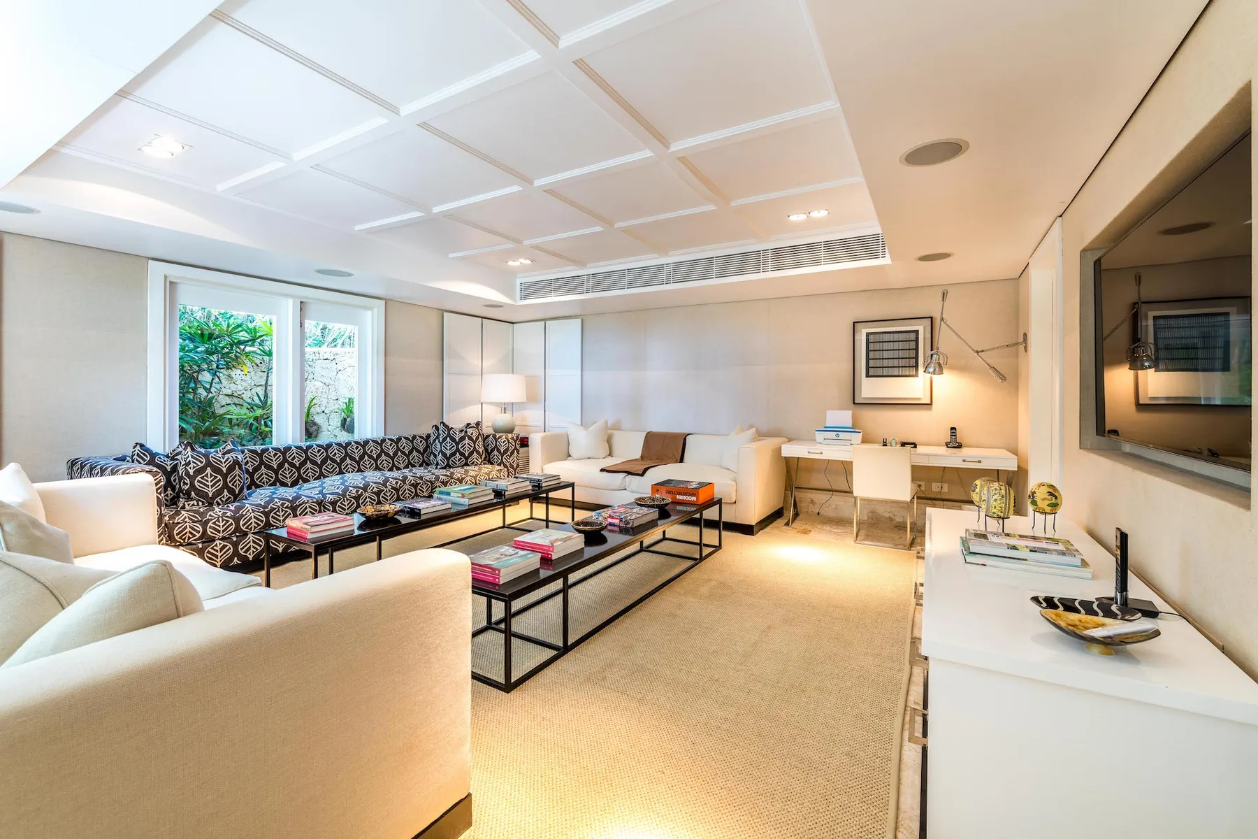 A bright living room with seating, low tables, and a dining area.