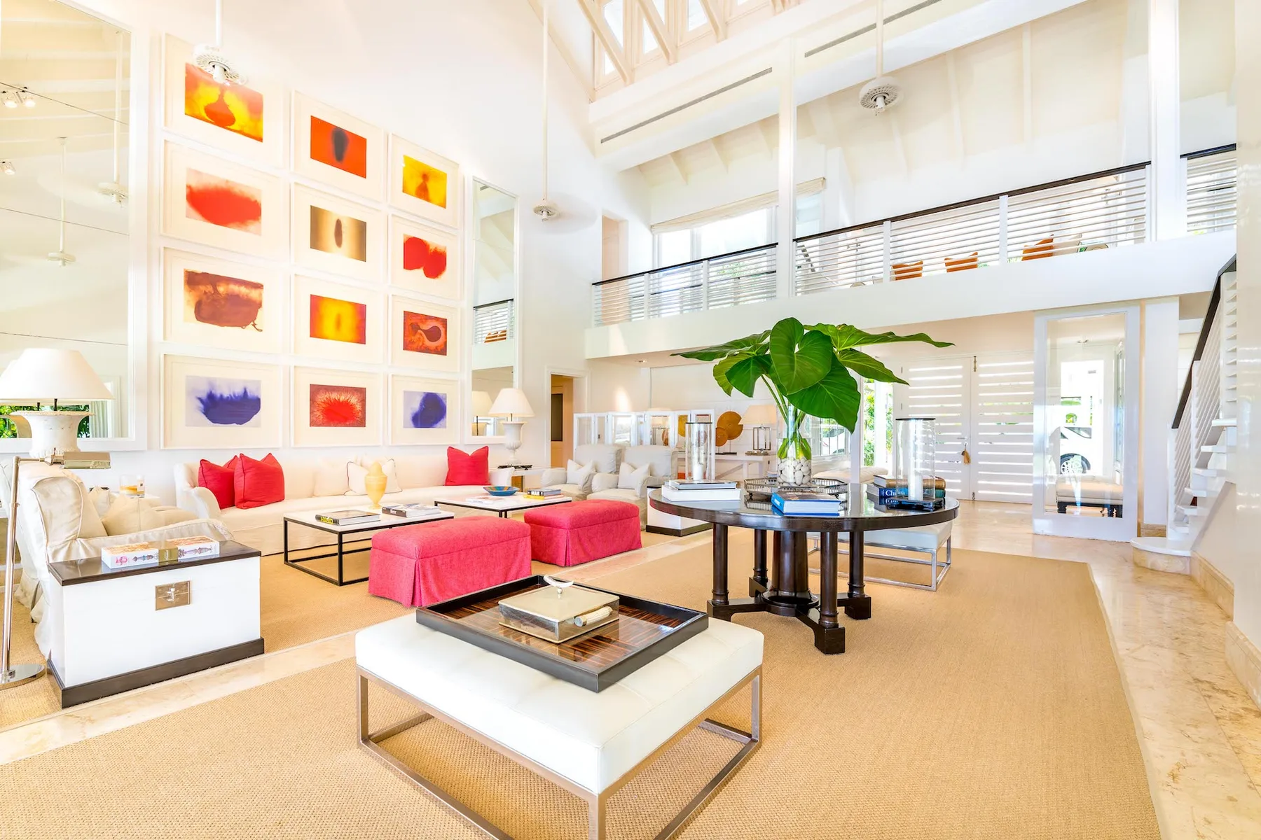 A bright double-height living room with colorful framed artwork and lounge seating.