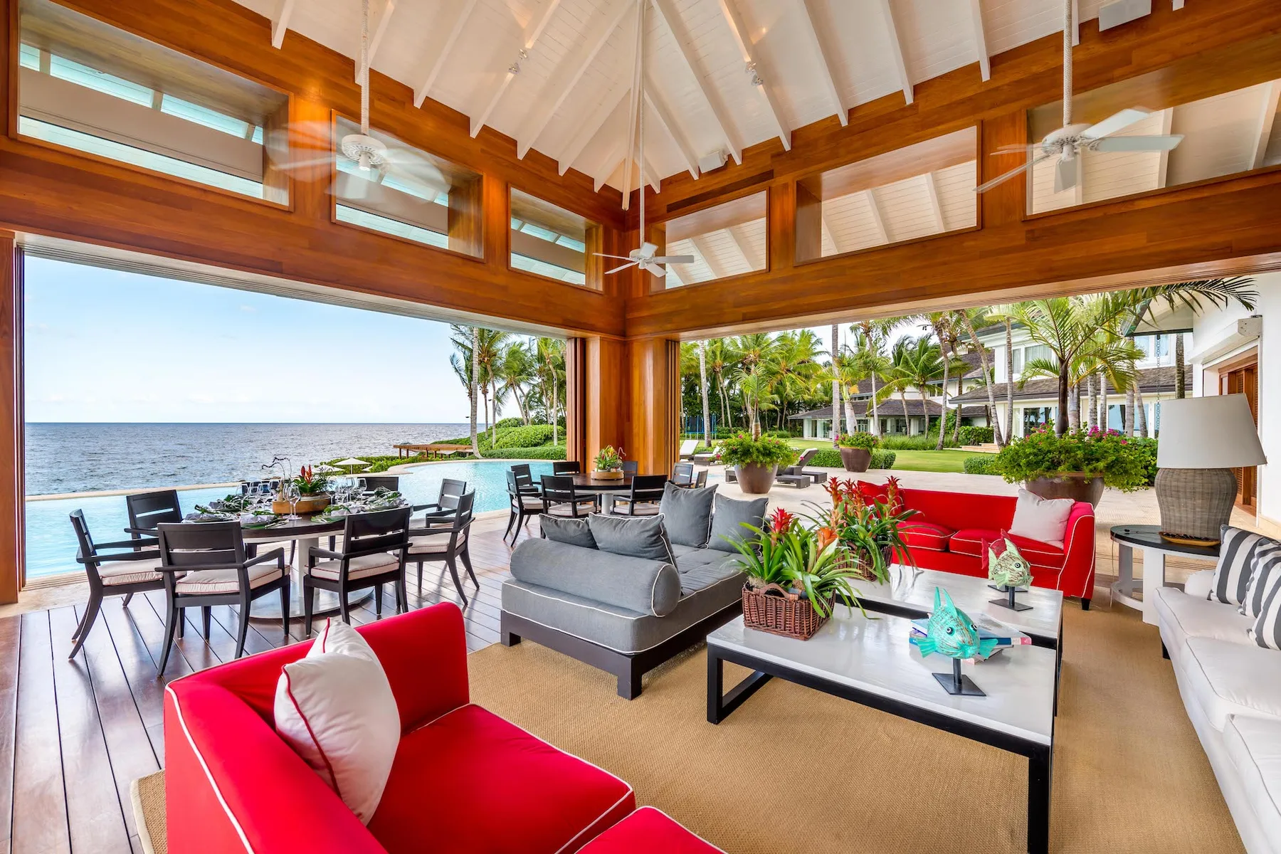 An open-plan lounge with red and gray seating overlooks the ocean.