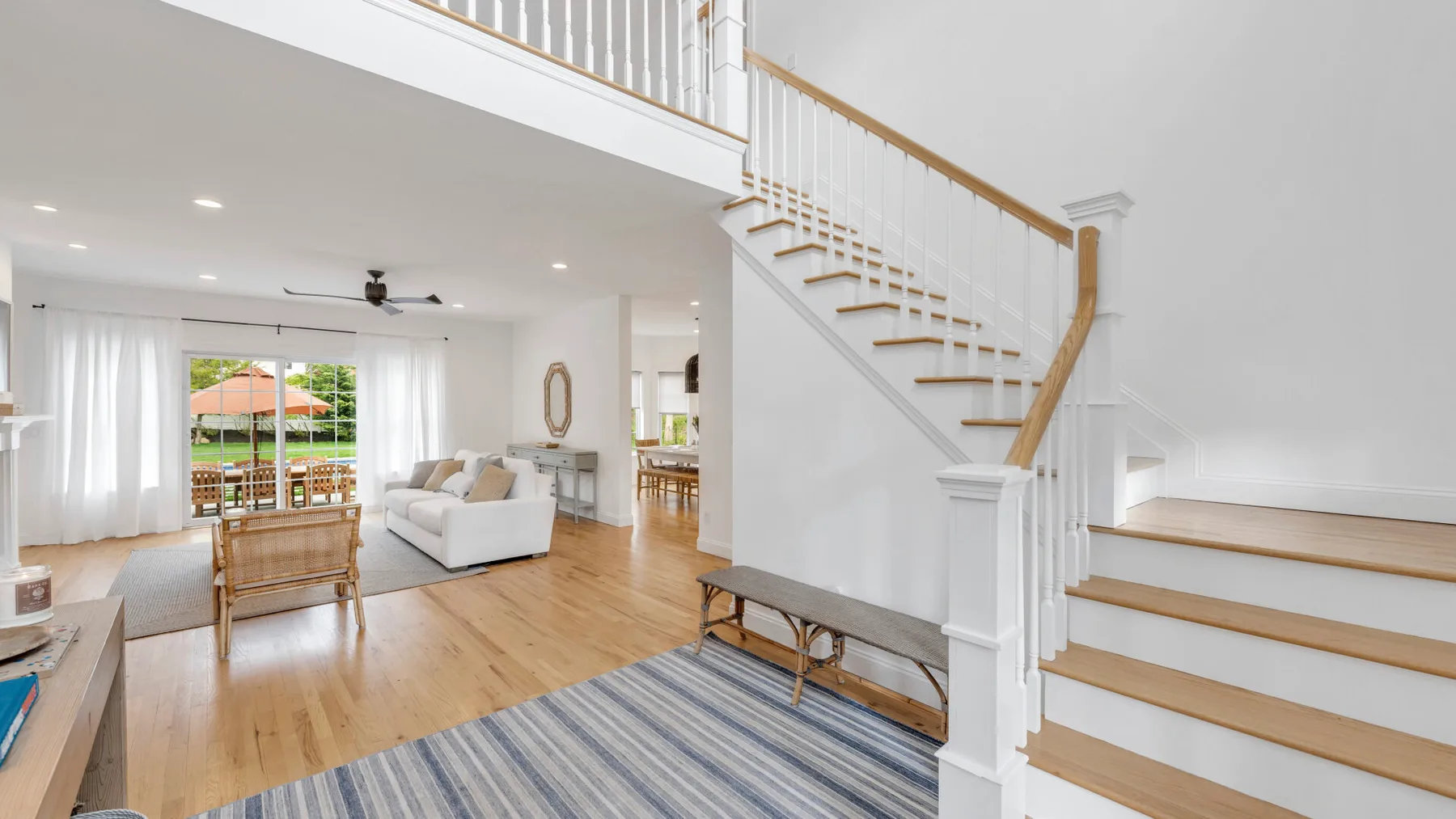 A bright living room opens onto a dining area beside a staircase.