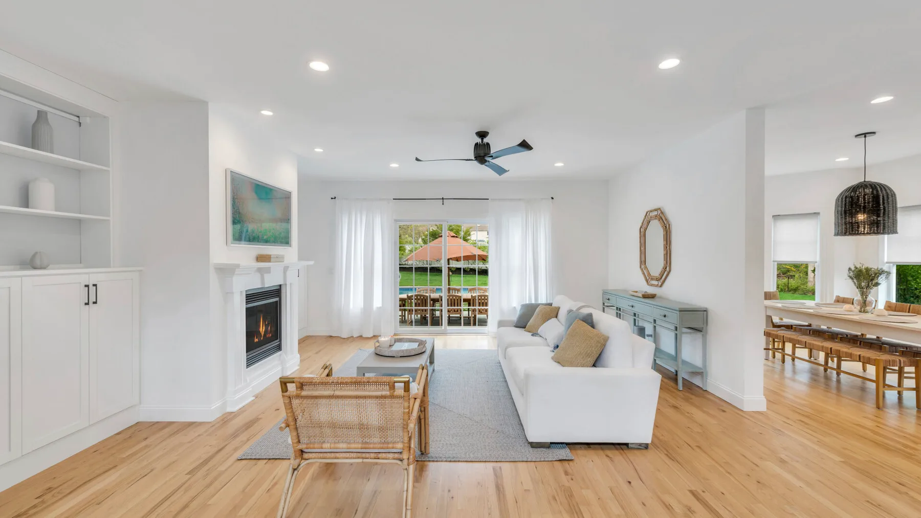Bright living room with white seating, a fireplace, and doors opening to a patio.