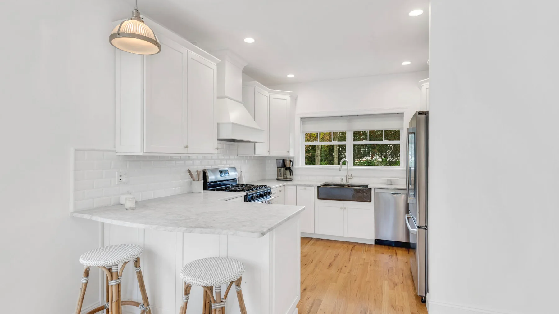 A bright kitchen with white cabinetry, a central island, and a window above the sink.