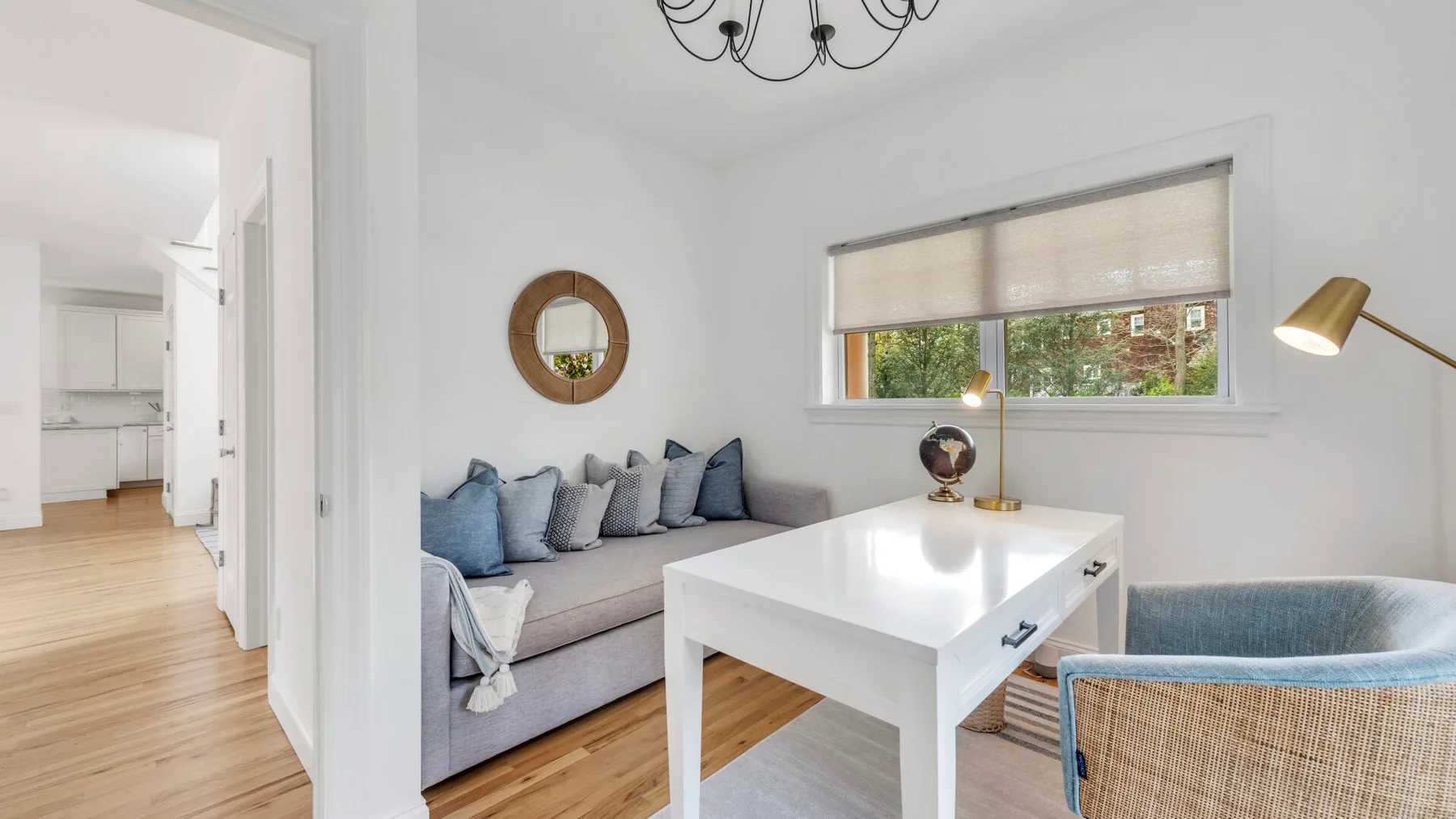 A bright living room with seating, a white table, and a wide window.
