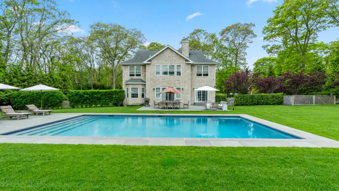 A house and swimming pool sit beyond a broad green lawn.