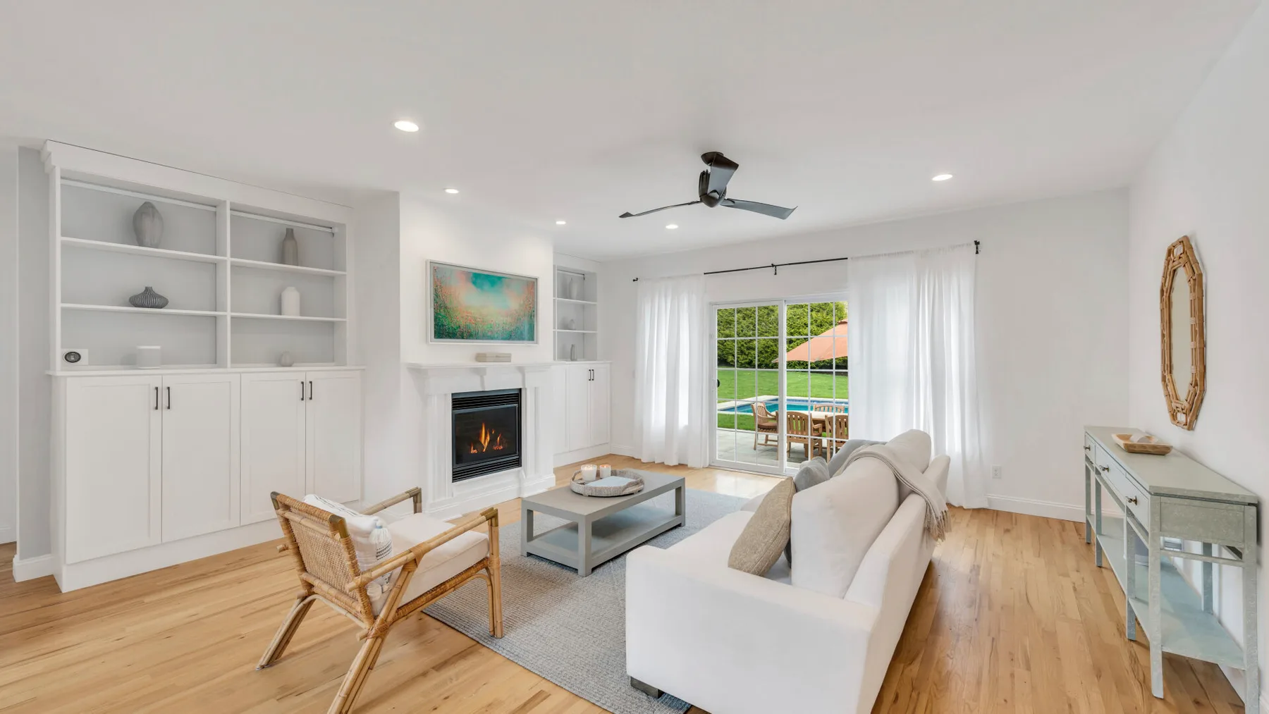 A bright living room with seating, built-in shelves, and large windows.