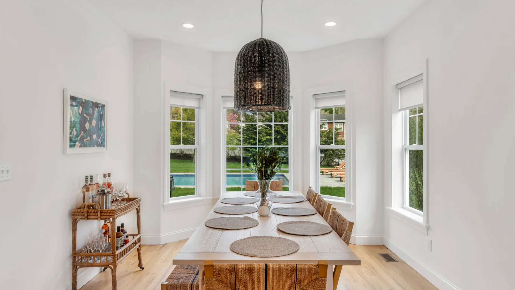 Bright dining area with a long table, large windows, and a hanging pendant light.