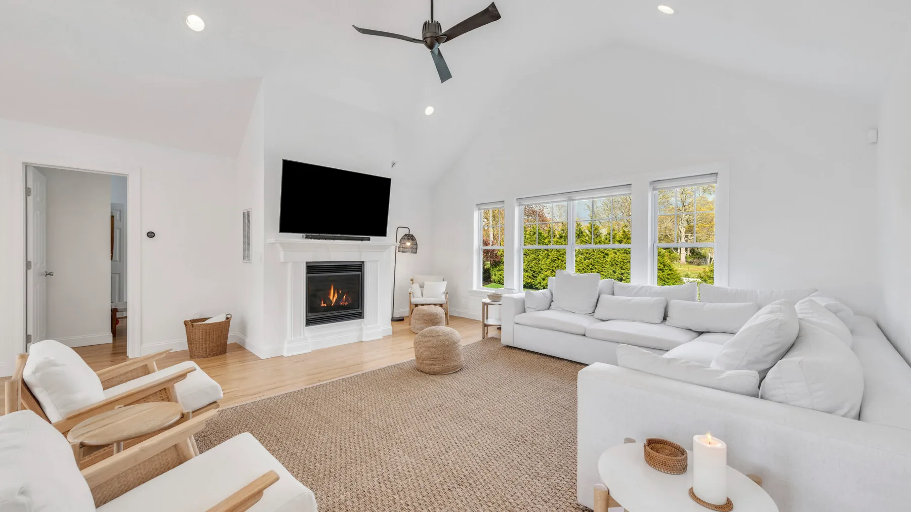 A bright living room with a large sectional sofa, fireplace, and wide windows.