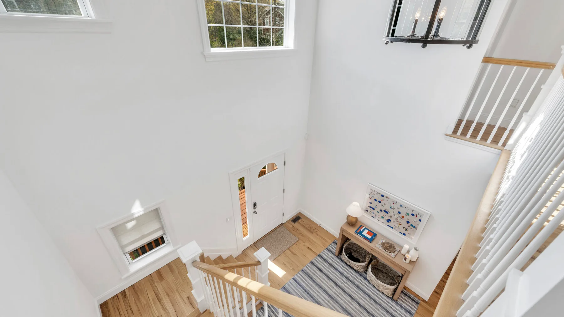 A bright interior landing with a wooden staircase, striped rug, and windows.