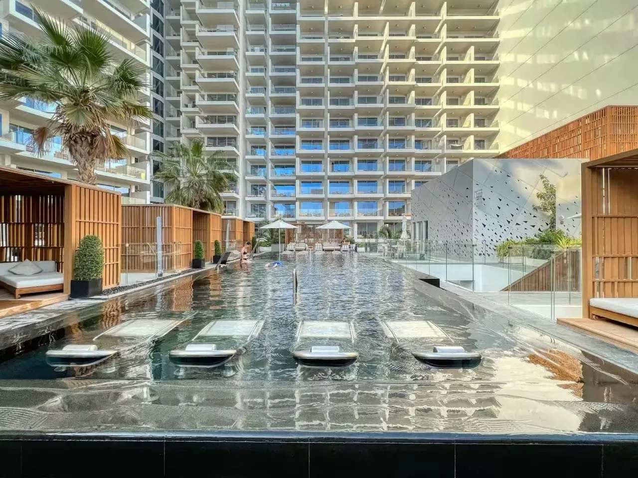 Una piscina al aire libre está rodeada de edificios modernos, con asientos junto al agua.