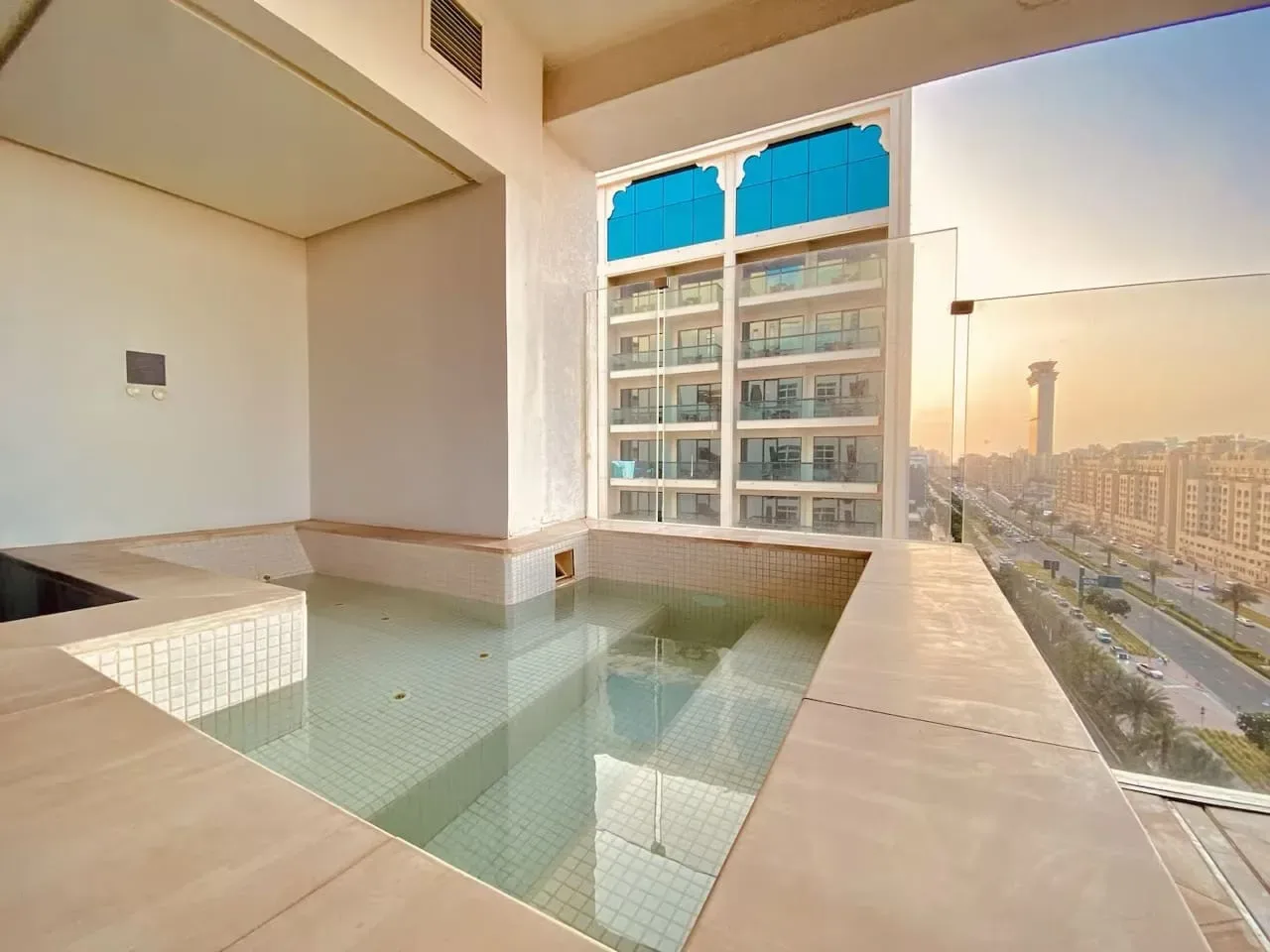 Una piscina interior está junto a grandes ventanales con vistas a edificios cercanos.