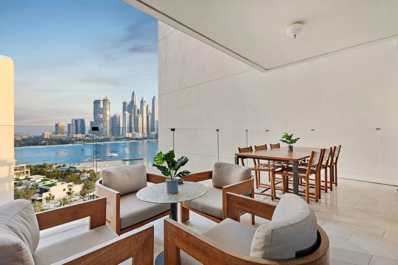 Una luminosa terraza con asientos da a un horizonte junto al agua y tiene una mesa de comedor cerca.