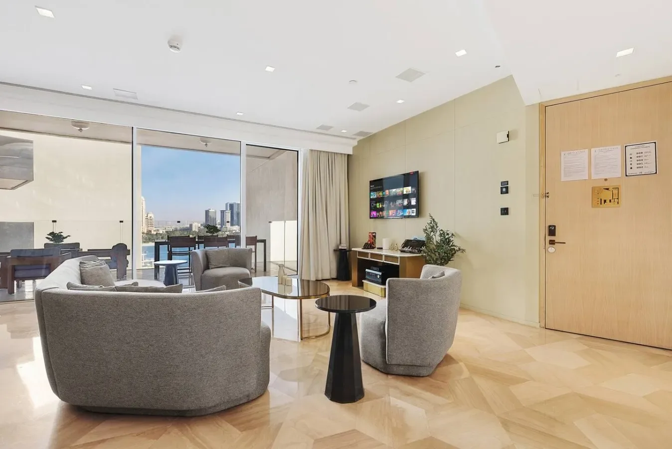 Una sala luminosa con asientos, un televisor y grandes ventanas con vistas a la ciudad.