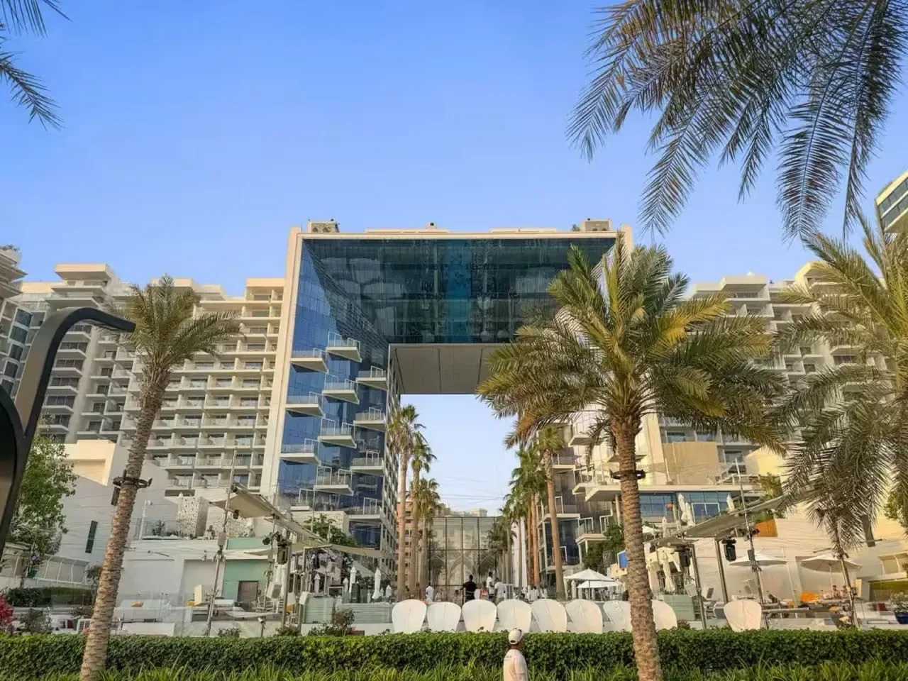 Un complejo hotelero moderno con un puente de vidrio sobre la entrada central.