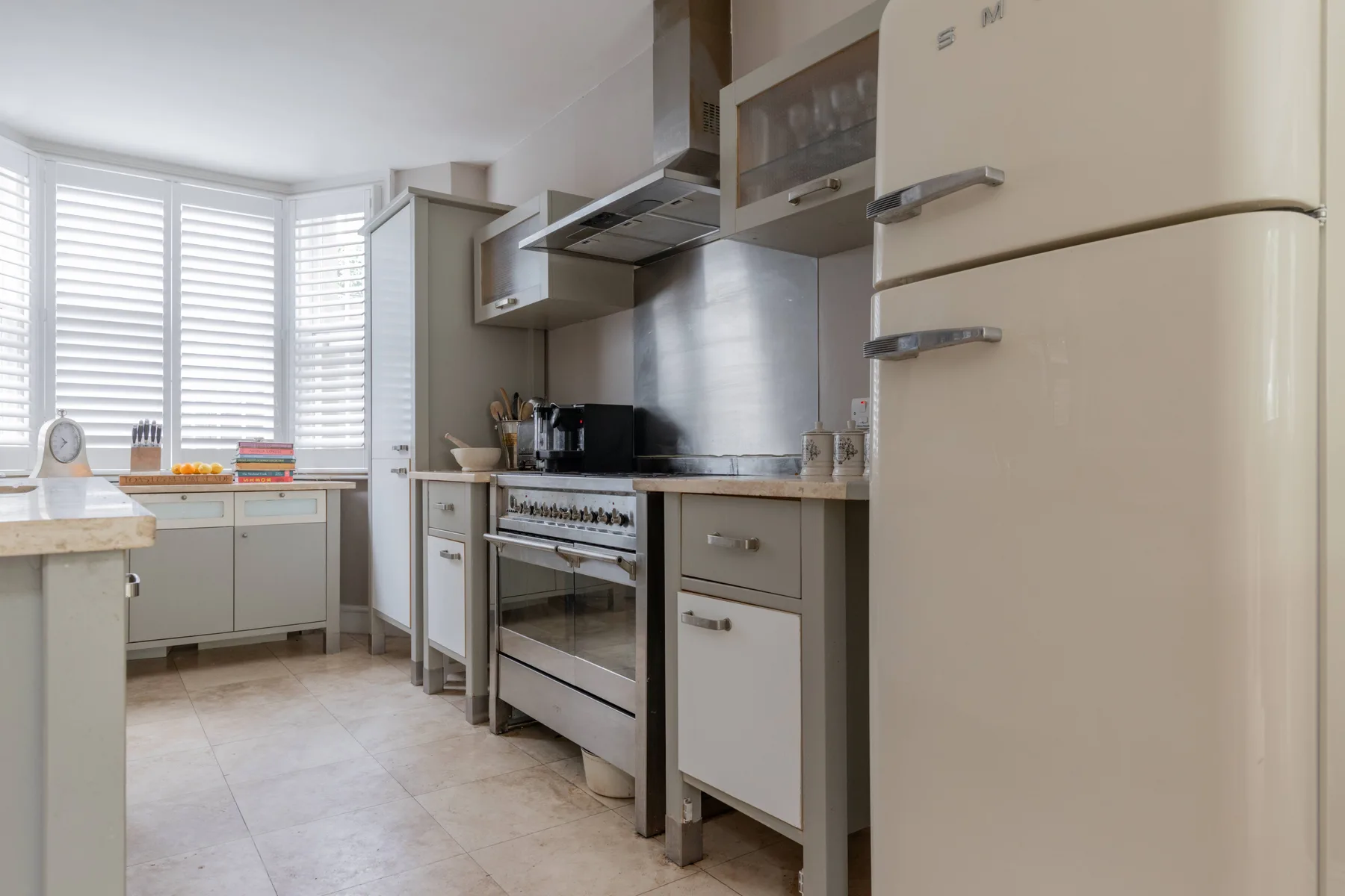 A bright kitchen with white cabinets, a stove, and a large refrigerator.