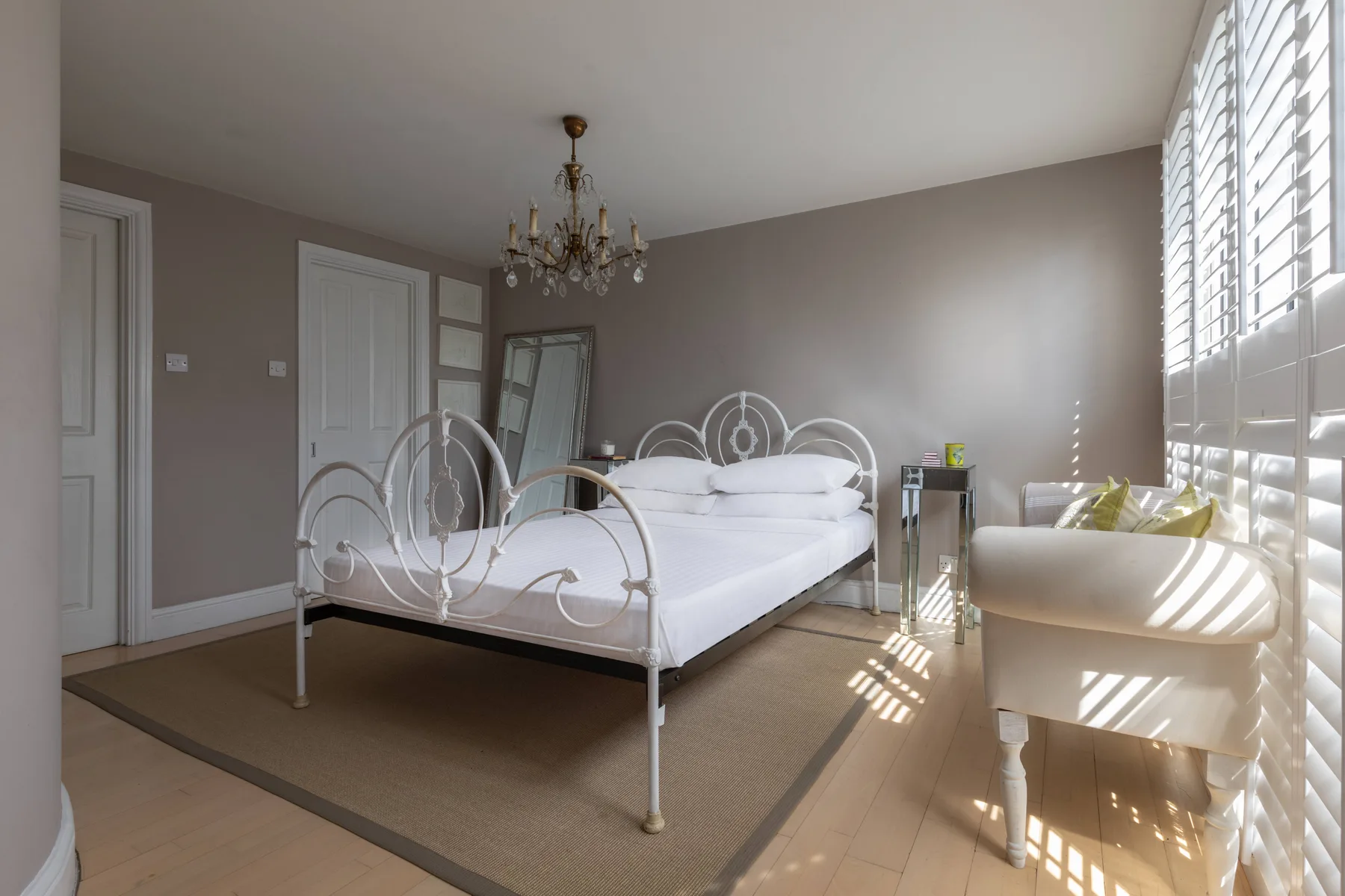 Un dormitorio luminoso con una cama blanca y luz del sol entrando por la ventana.