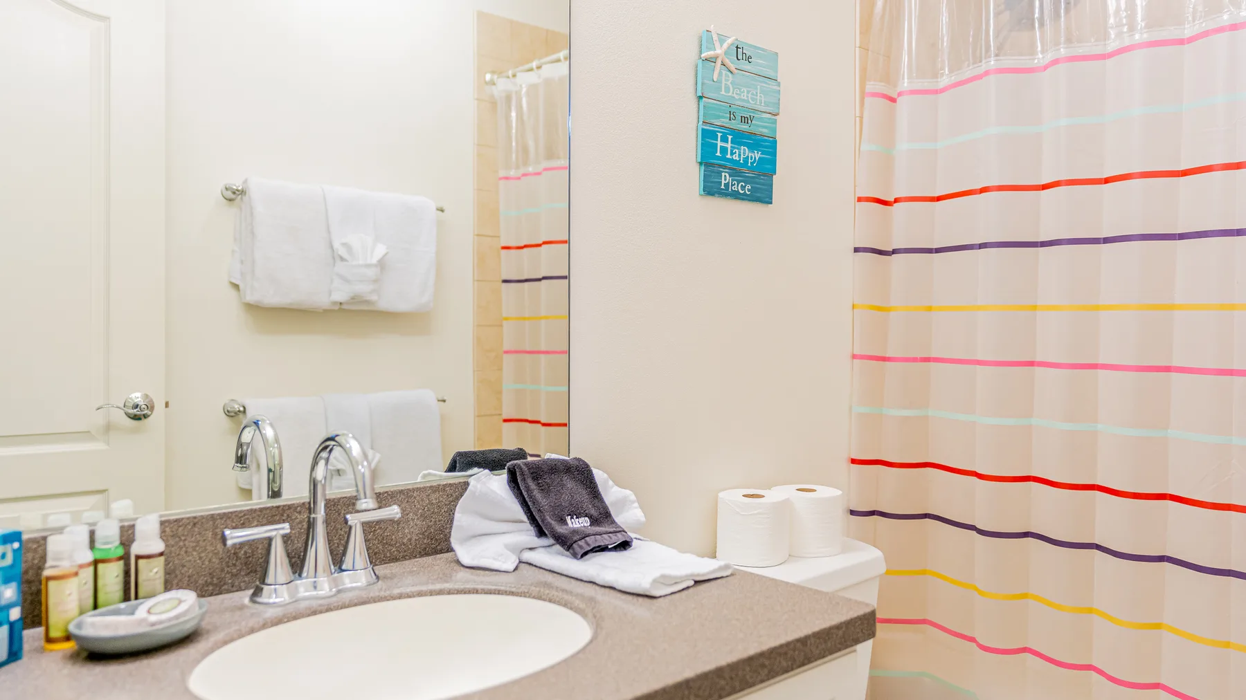 Un tocador de baño con lavabo y una cortina de ducha a rayas.