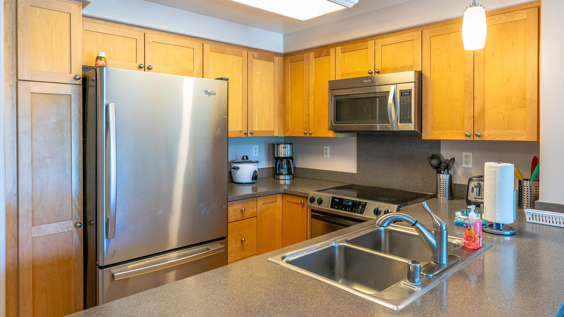 Una cocina con gabinetes de madera, electrodomésticos de acero inoxidable y un fregadero doble.