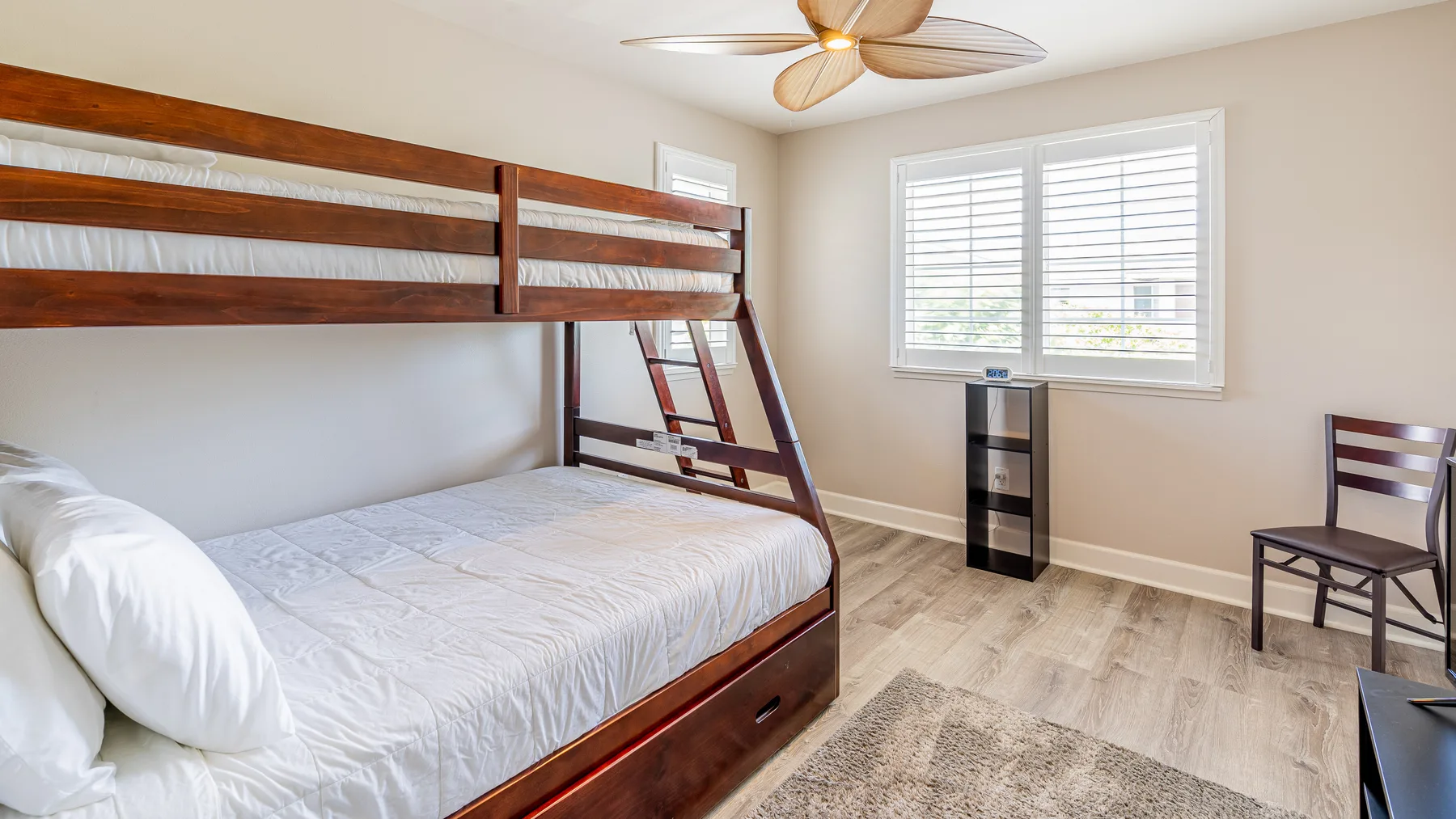 Un dormitorio con una litera de madera, una ventana y una silla.