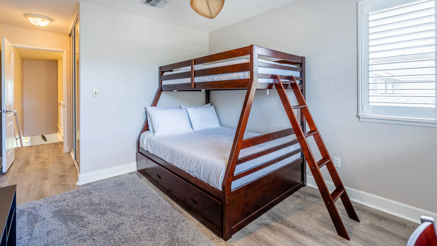Un dormitorio con una litera de madera, una ventana y una alfombra.