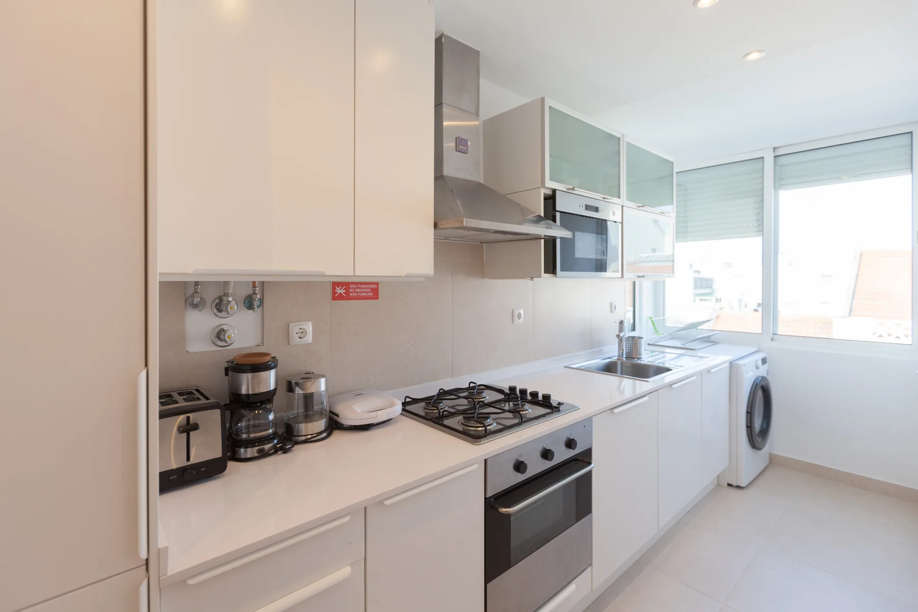 A bright kitchen with white cabinets, a stovetop, and a sink.