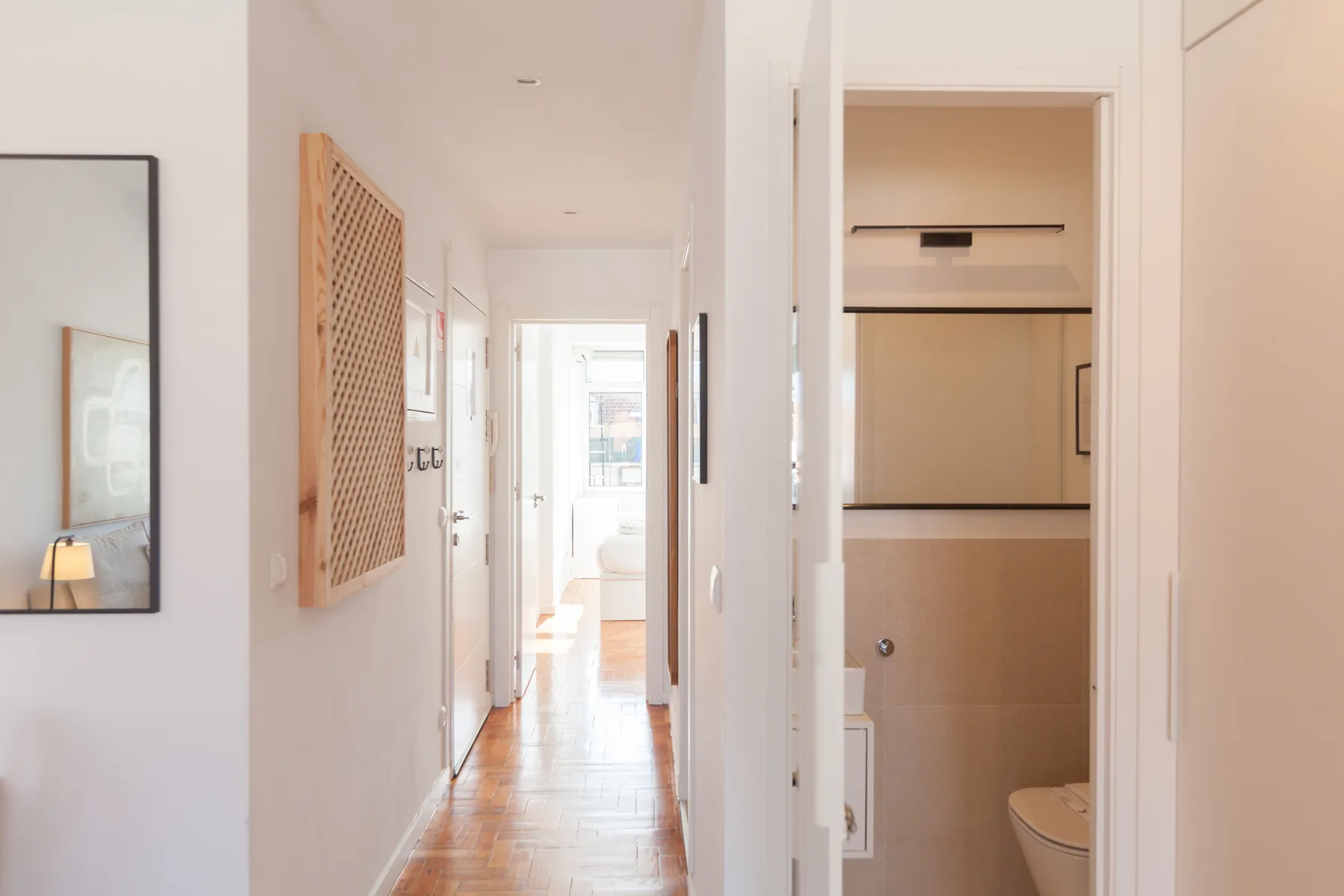 A bright hallway leads past an open bathroom doorway.