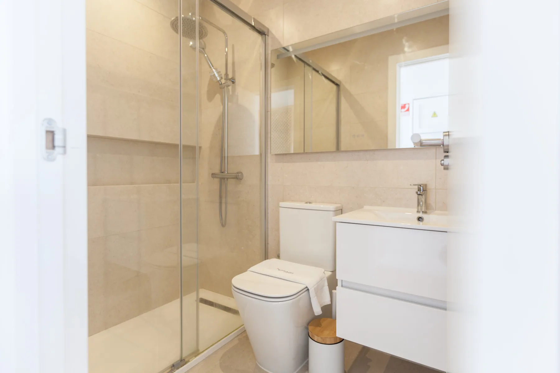 A bathroom with a glass shower, toilet, and sink.