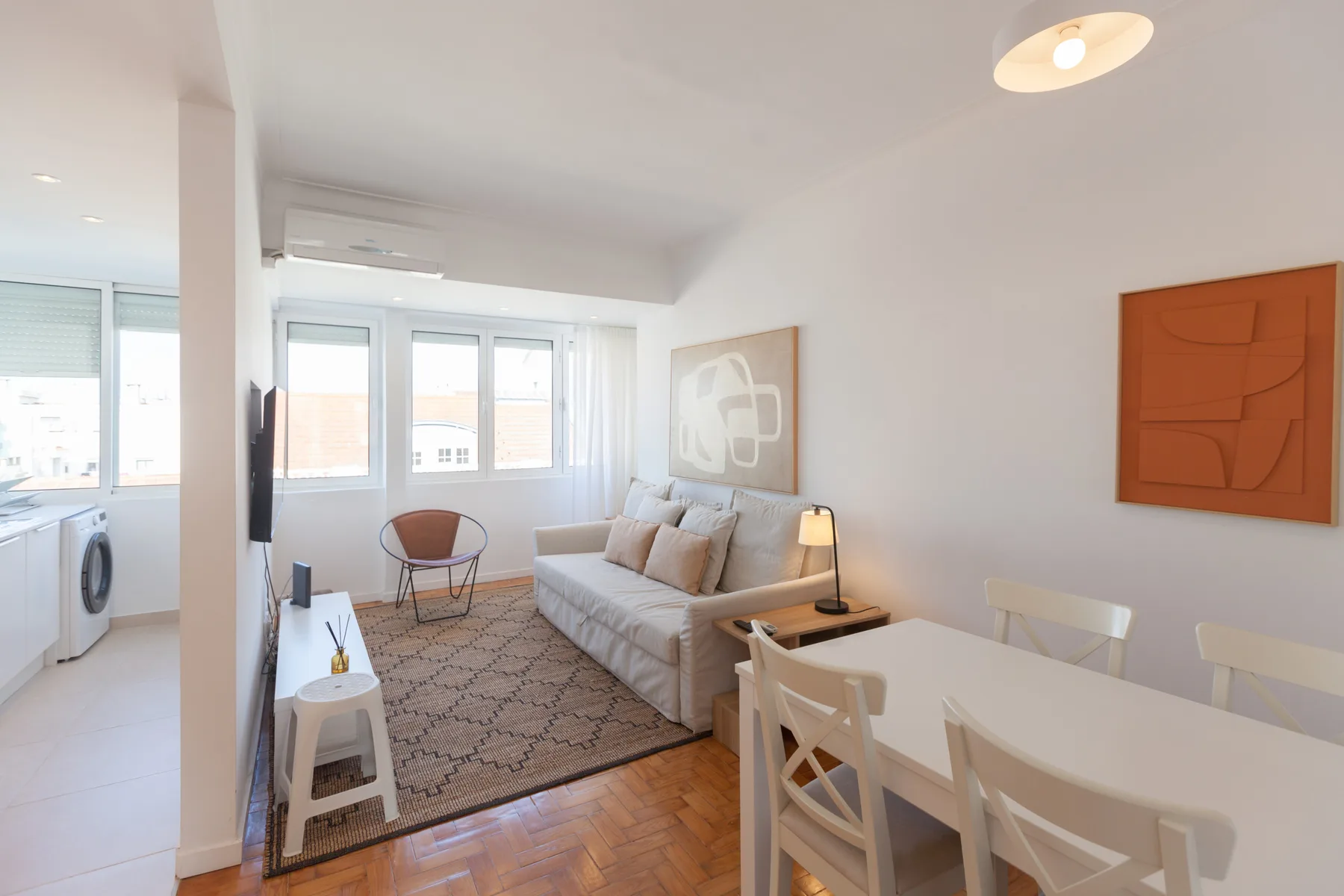A bright living and dining area with a sofa, table, and large windows.