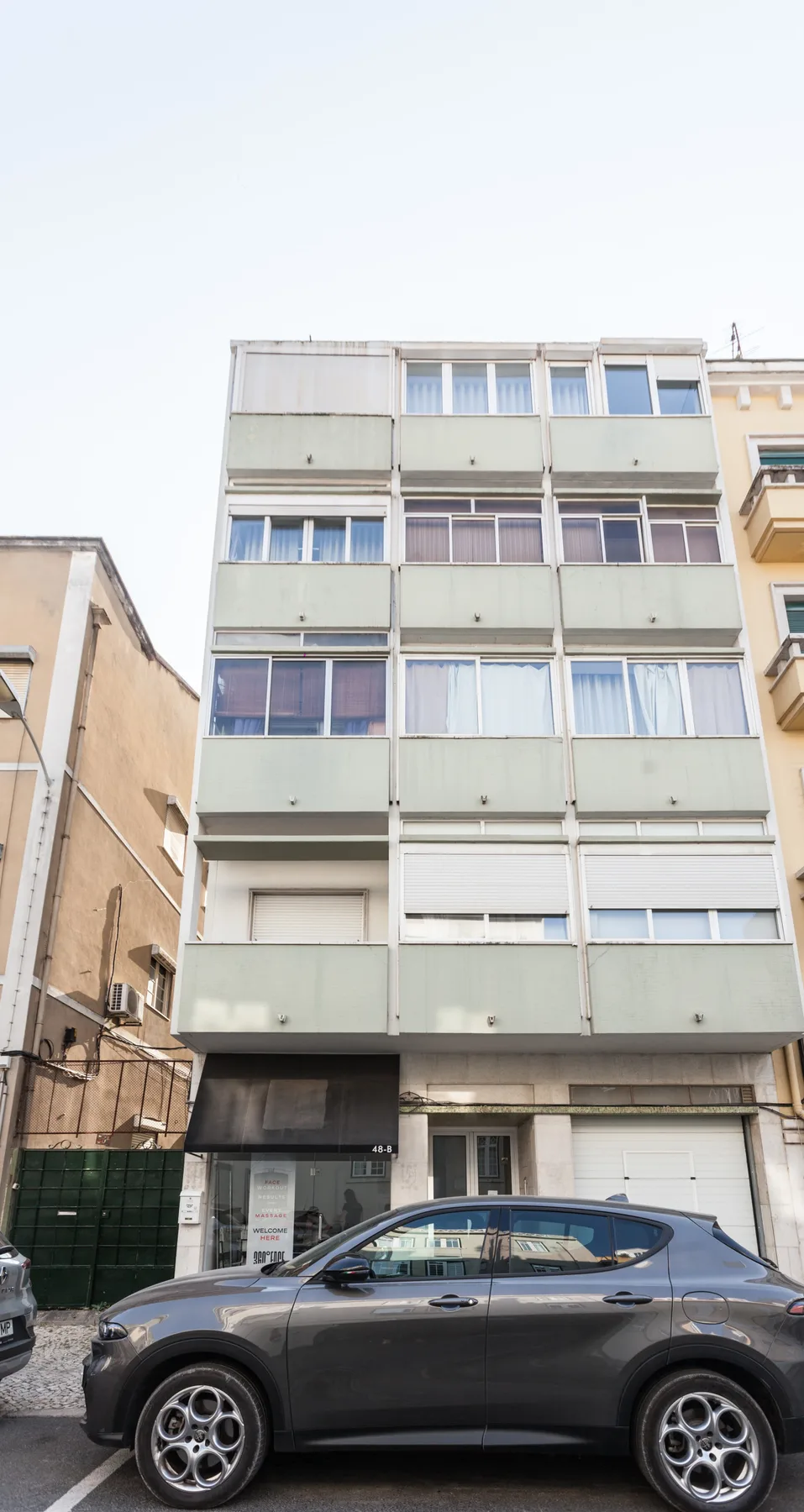 A multi-story building facade with rows of windows above parked cars.