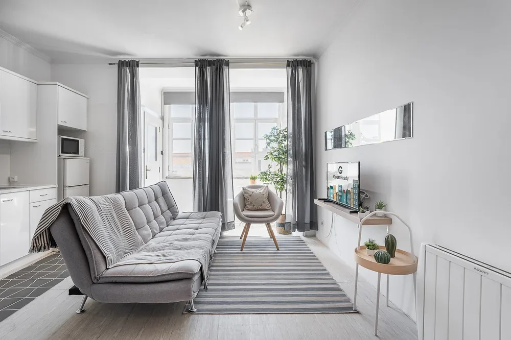A bright living room with gray seating, striped rug, and windows.