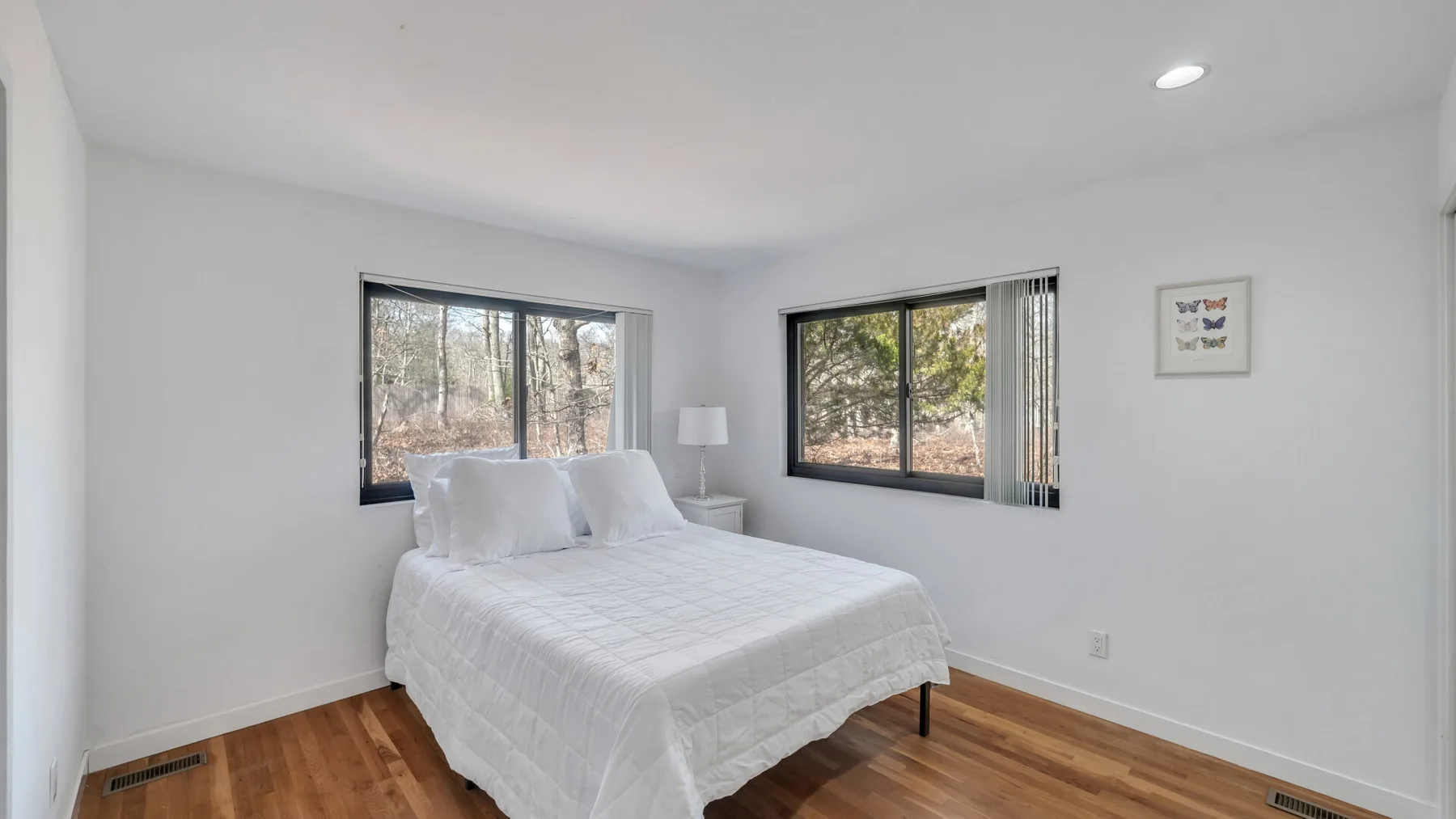 A bright bedroom with a bed beside two windows.