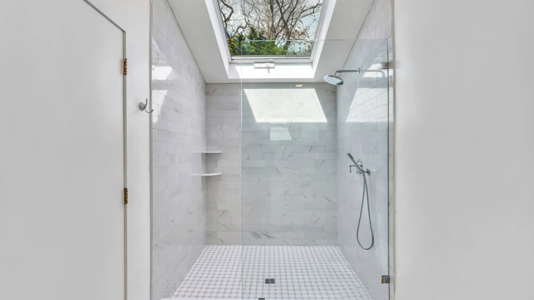 A bright tiled shower beneath a skylight.