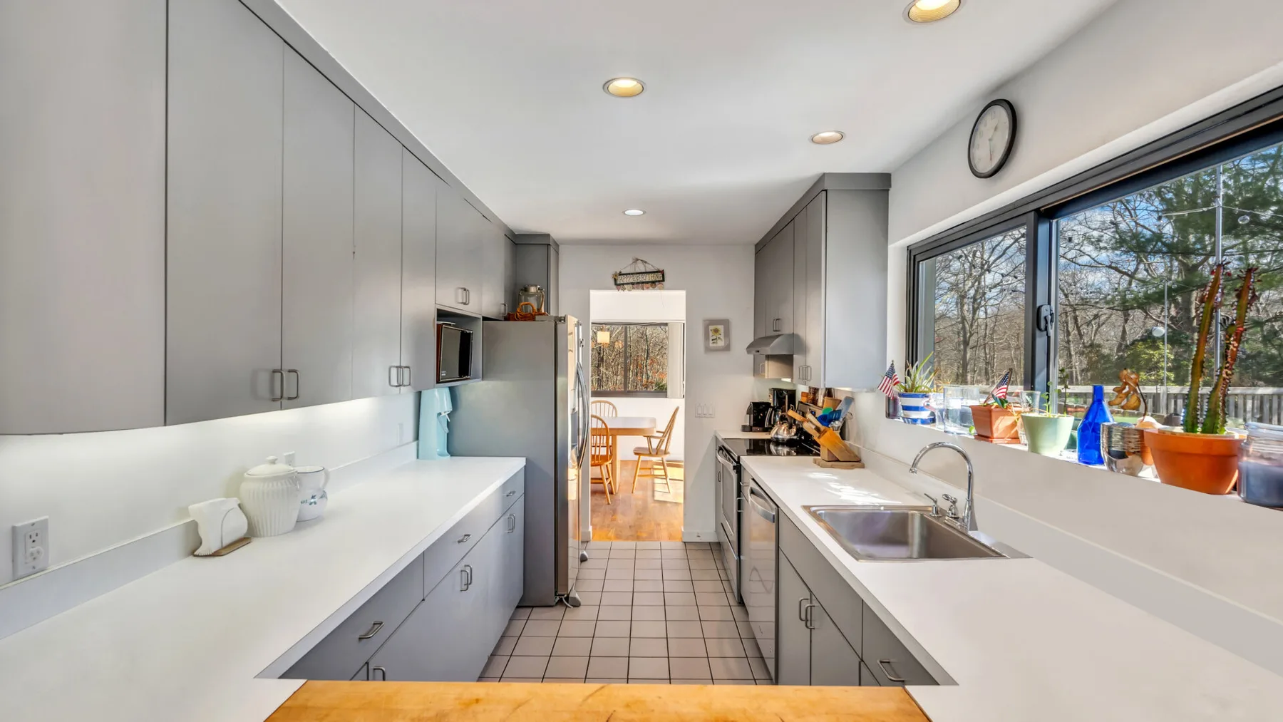 A bright kitchen with counters, cabinets, and a large window.