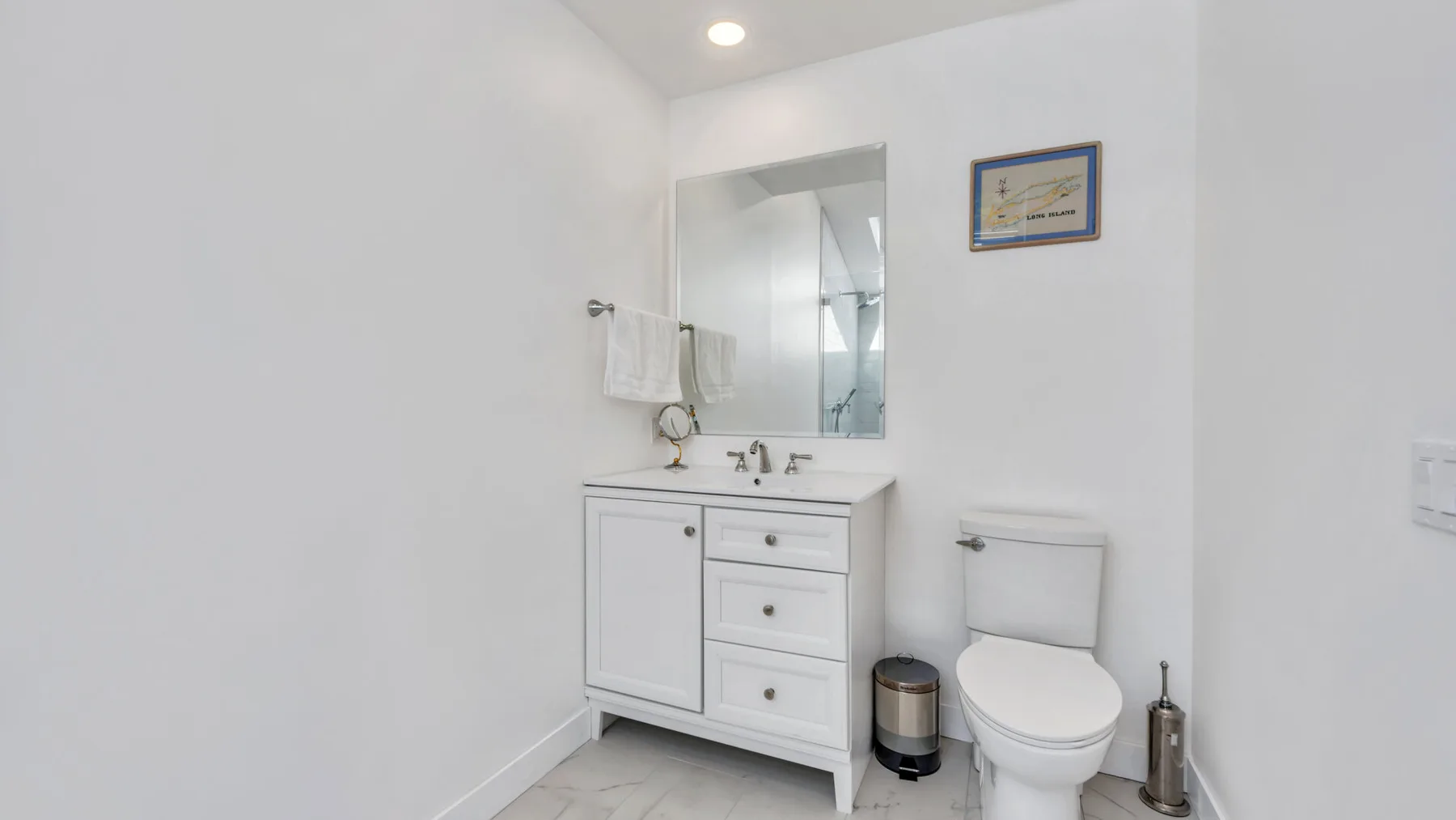 A bright bathroom with a vanity, mirror, and toilet.