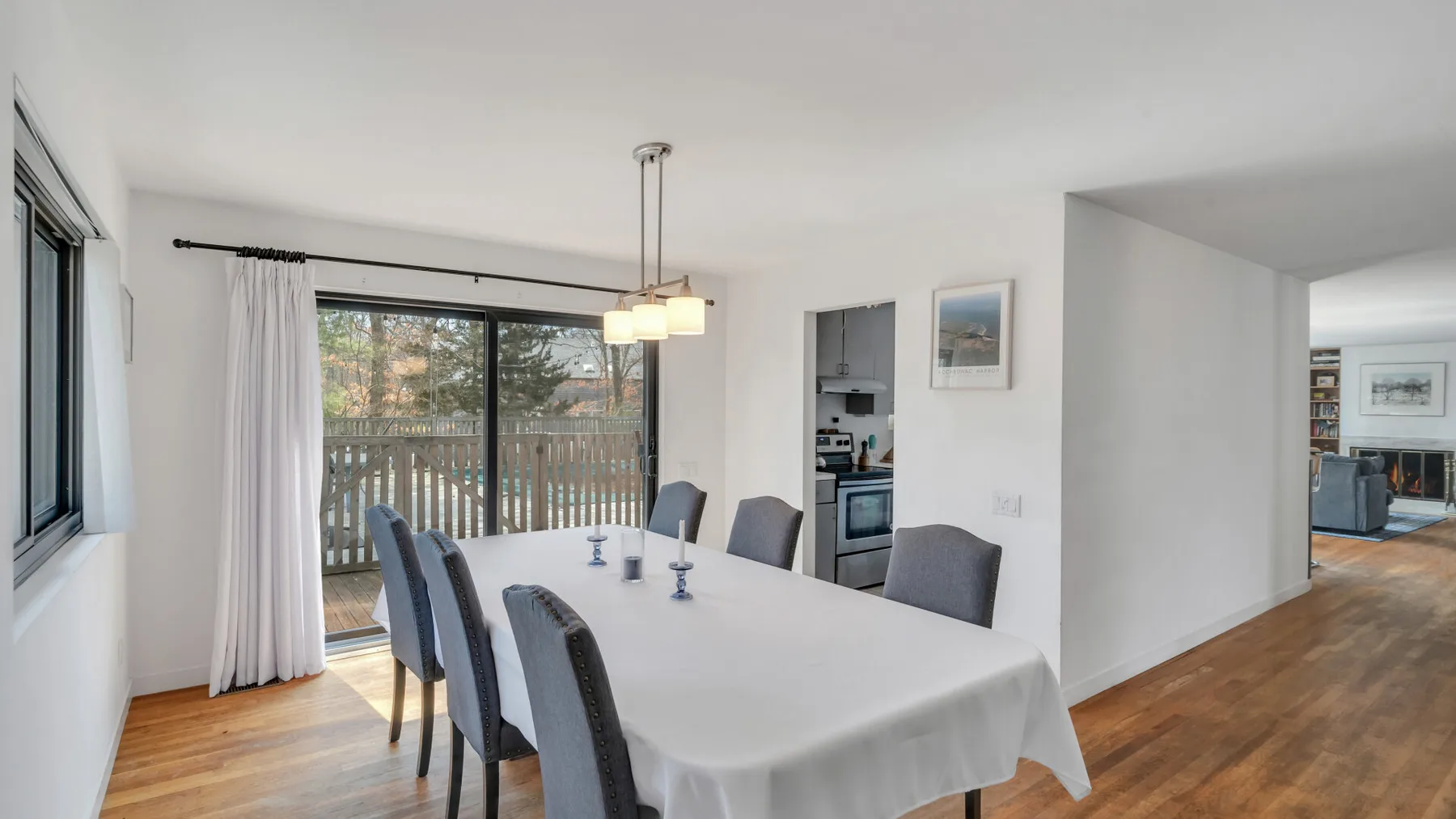 A dining area with a table and chairs beside a large window overlooking a balcony.