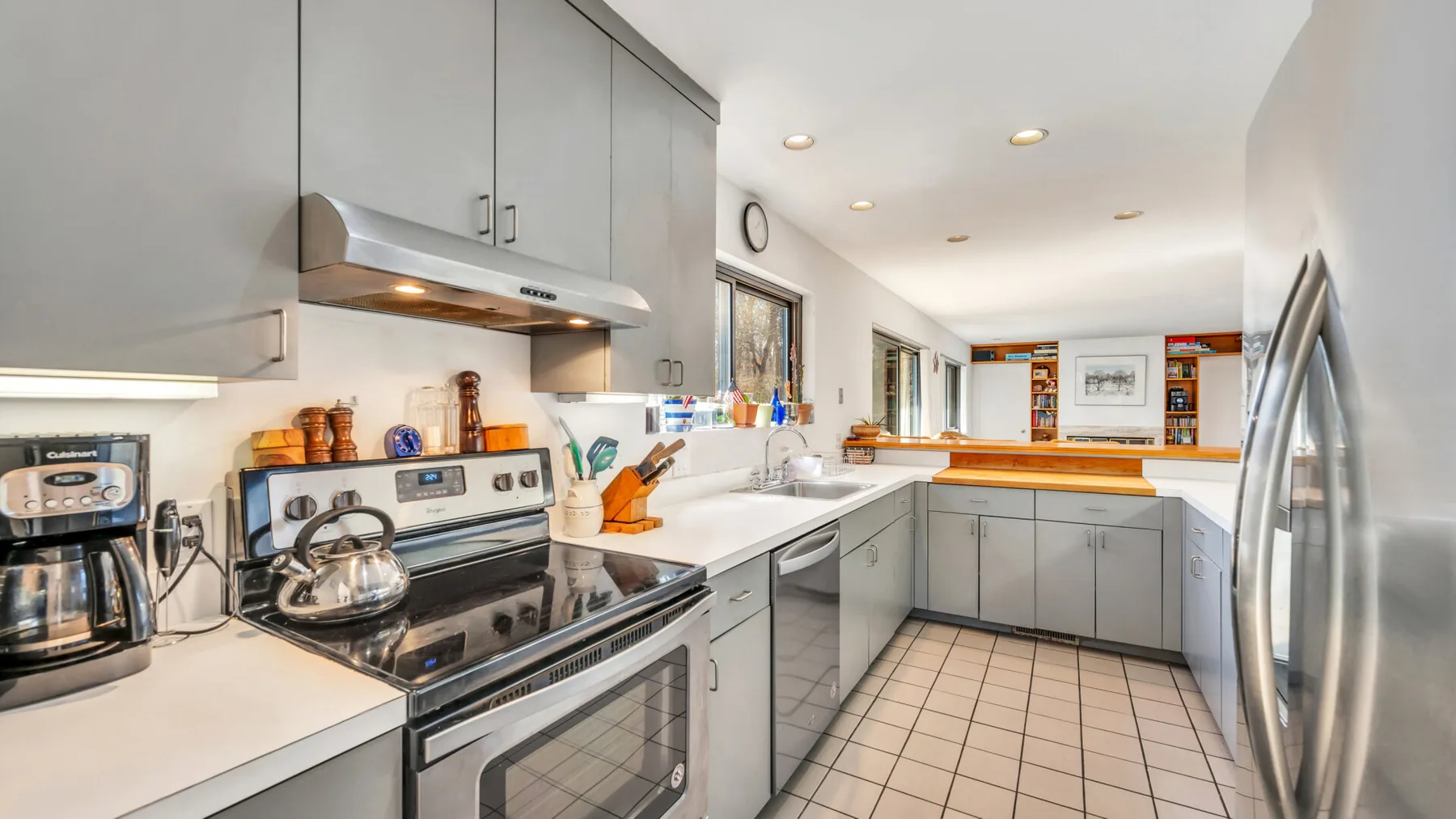 A bright kitchen with counters, cabinets, and stainless steel appliances.