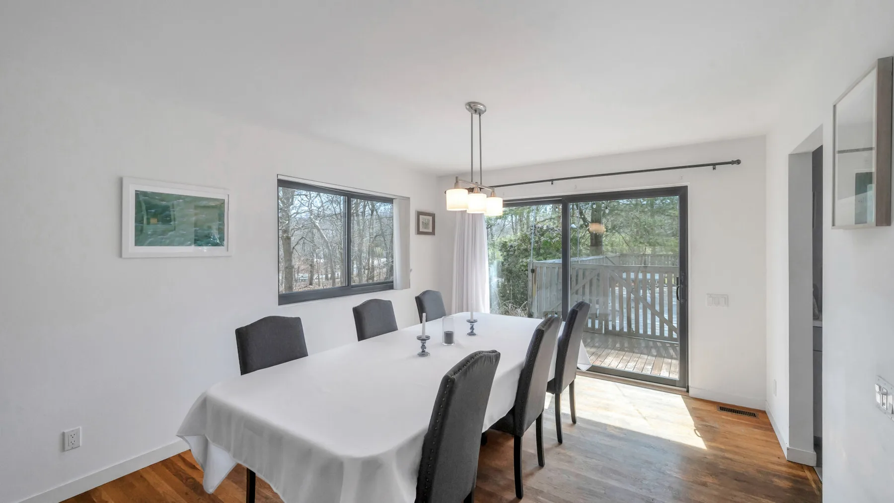 A dining area with a long table and chairs beside a sliding glass door.