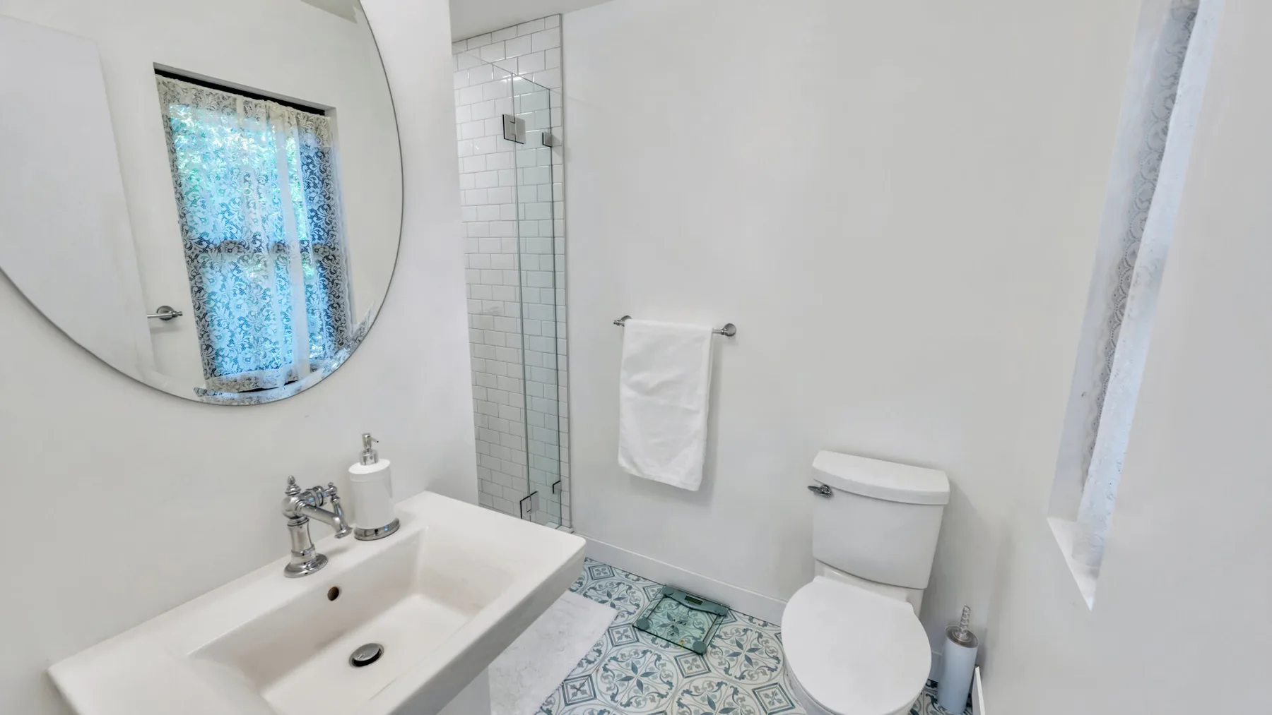 A bright bathroom with a sink, toilet, and tiled shower area.