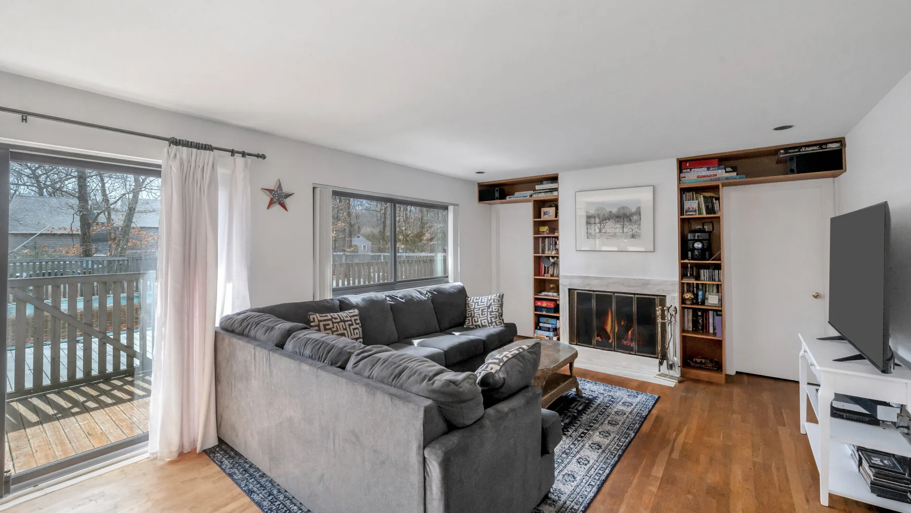 A living room with gray seating, a fireplace, and large windows.