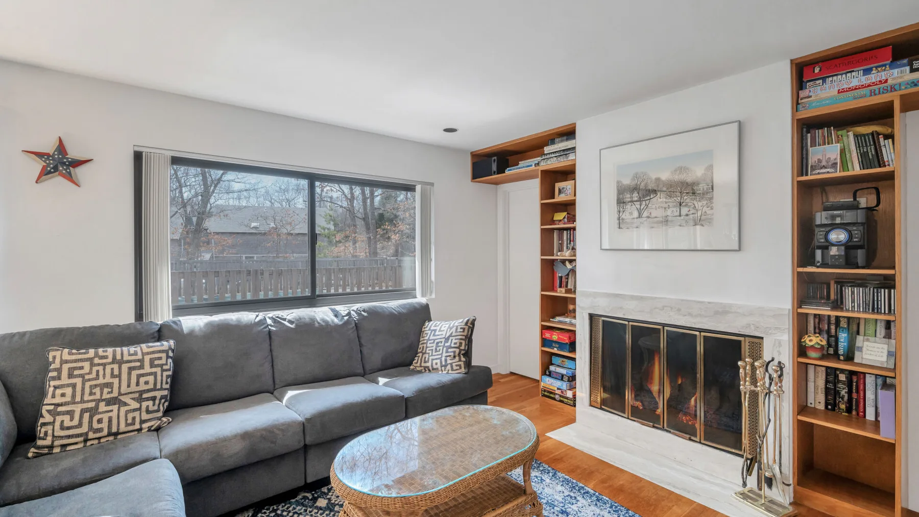 A living room with gray seating, a fireplace, and built-in bookshelves.