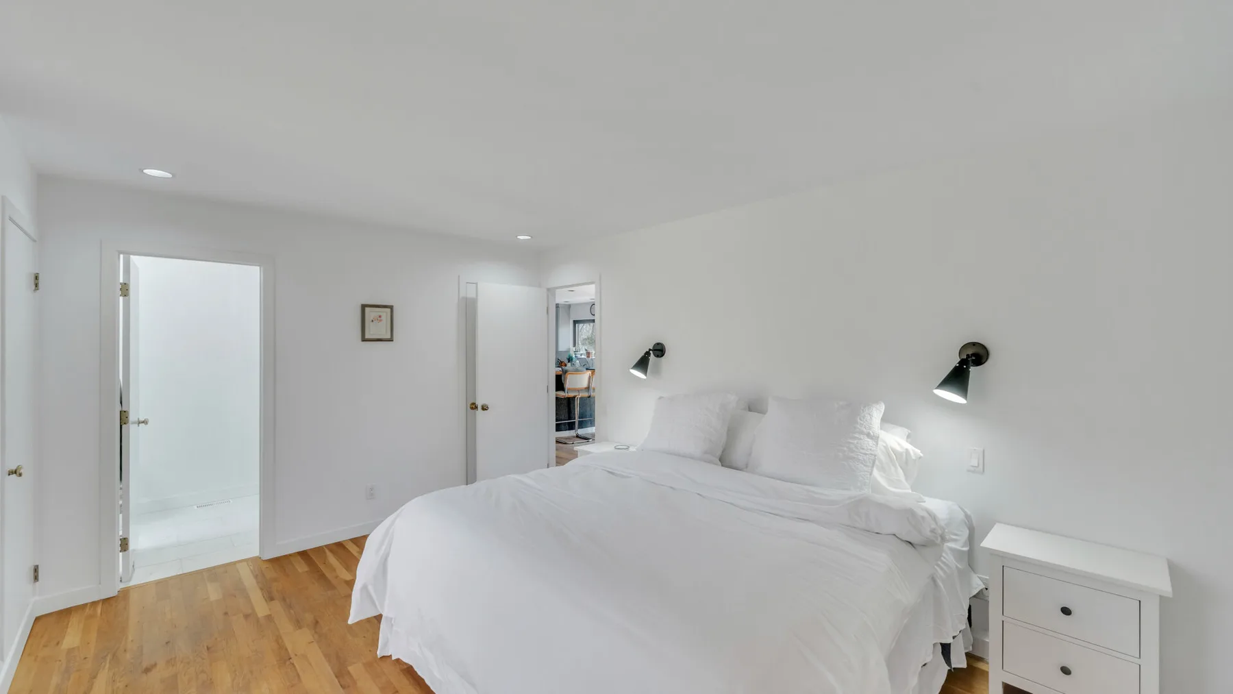 A bright bedroom with a large bed and white bedding.