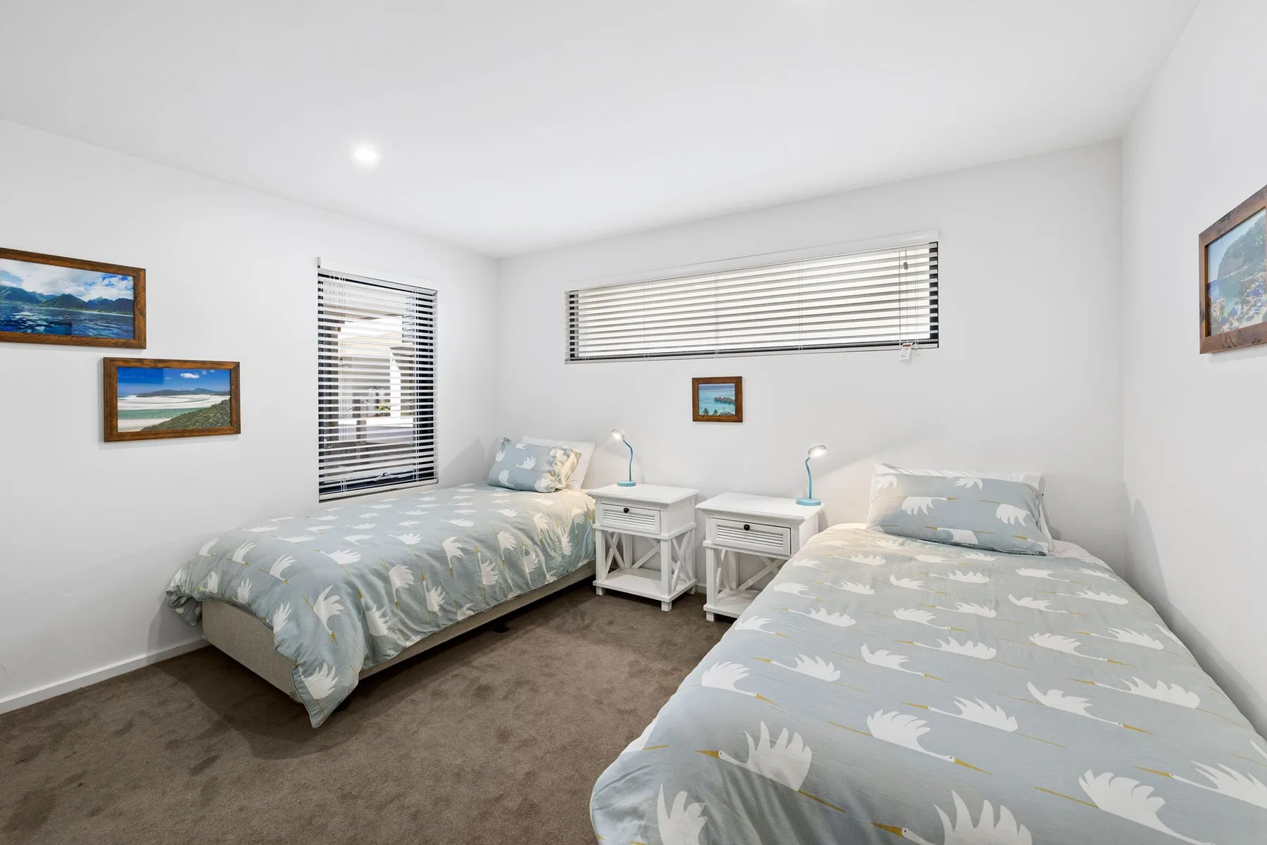 Un dormitorio luminoso con dos camas y ropa de cama clara con estampado.