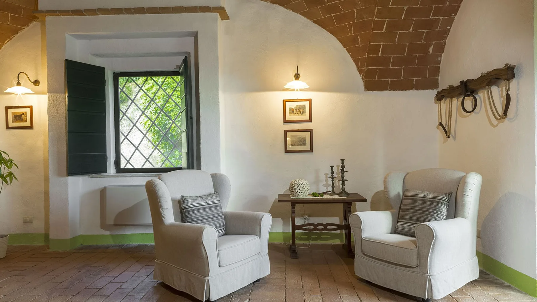 Una zona de estar con dos asientos tapizados y una mesa pequeña bajo un arco de ladrillo.