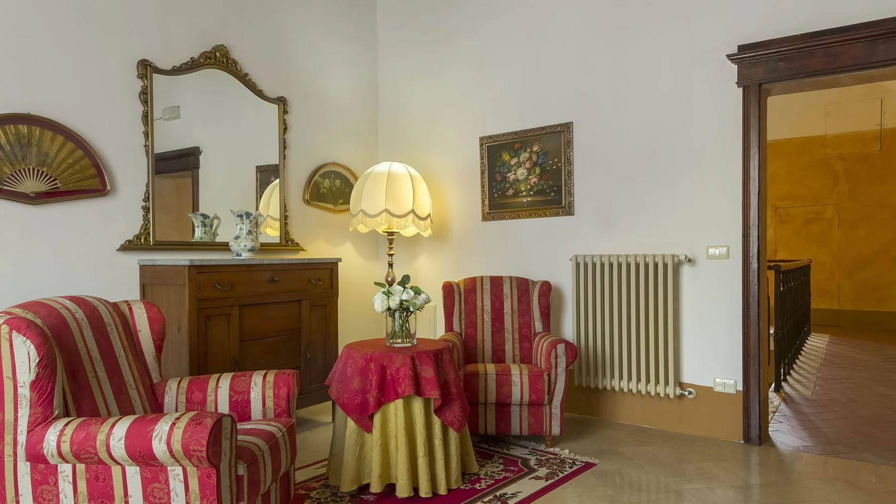 Una sala de estar con asientos a rayas alrededor de una mesa pequeña y una lámpara.