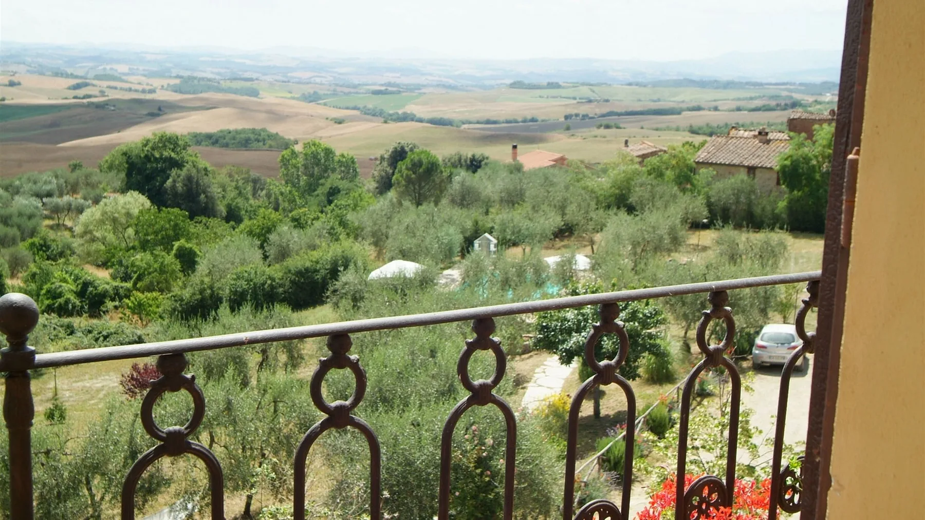 Un balcón da a un paisaje verde con campos ondulados.